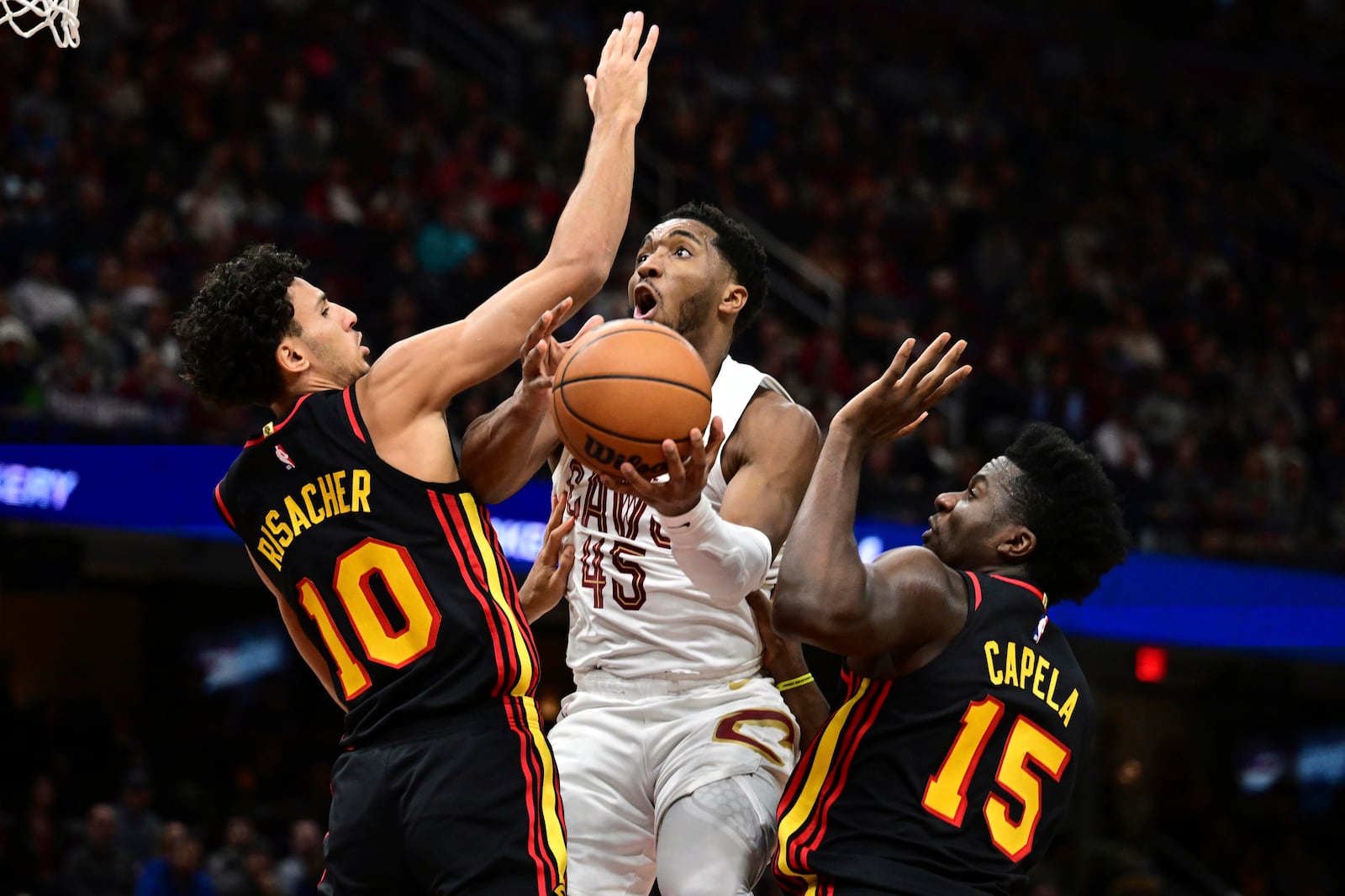 Cleveland Cavaliers guard Donovan Mitchell goes to the basket against Atlanta Hawks forward Zaccharie Risacher (10) and Atlanta Hawks center Clint Capela (15) in the first half of an NBA basketball game, Wednesday, Nov. 23, 2024, in Cleveland. (AP Photo/David Dermer)