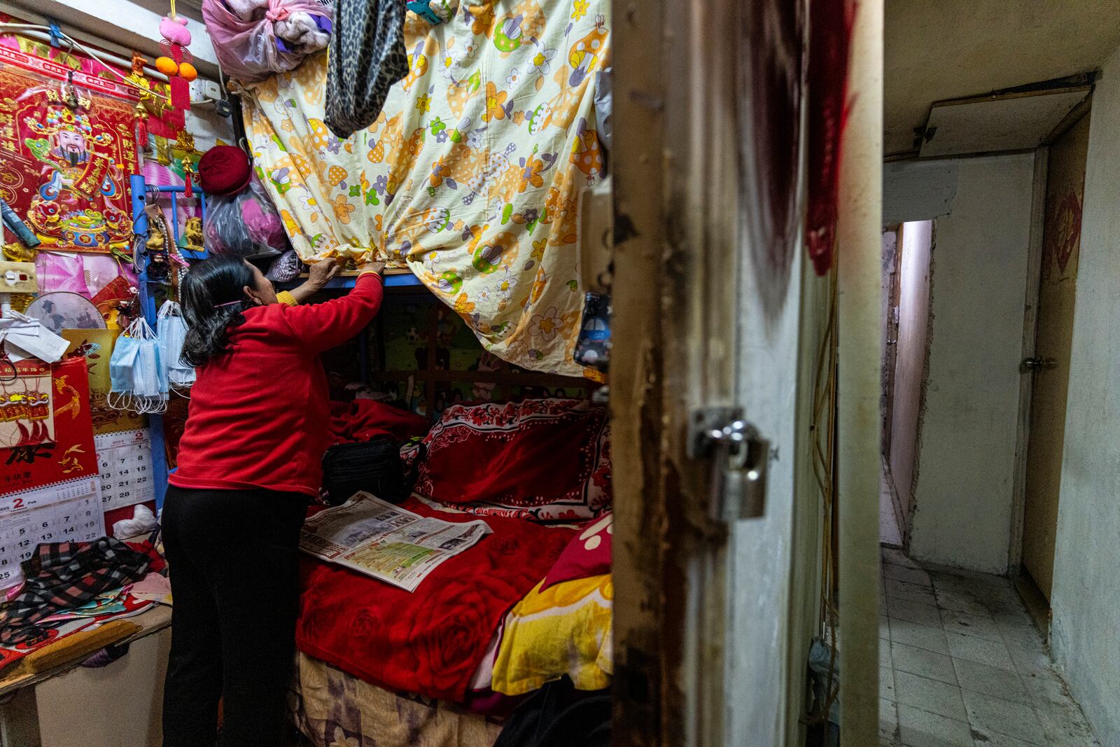 A resident adjusts the curtains over a bed at her subdivided flat in Sham Shui Po district of Hong Kong, on Feb. 6, 2025. (AP Photo/Chan Long Hei)