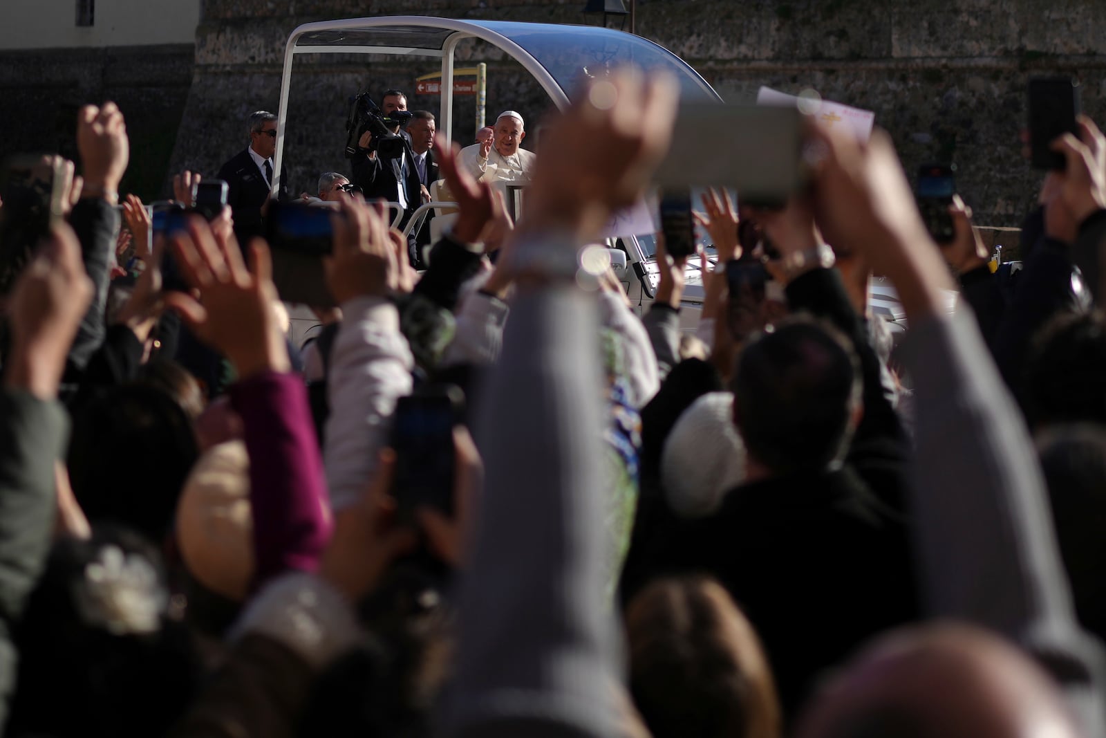 Faithful wave for Pope Francis Sunday, Dec. 15, 2024 in Ajaccio, Corsica island. Pope Francis' one-day visit to the French island of Corsica puts a dual focus on the Mediterranean, highlighting local traditions of popular piety on the one hand and migrant deaths and wars on the other. (AP Photo/Thibault Camus)