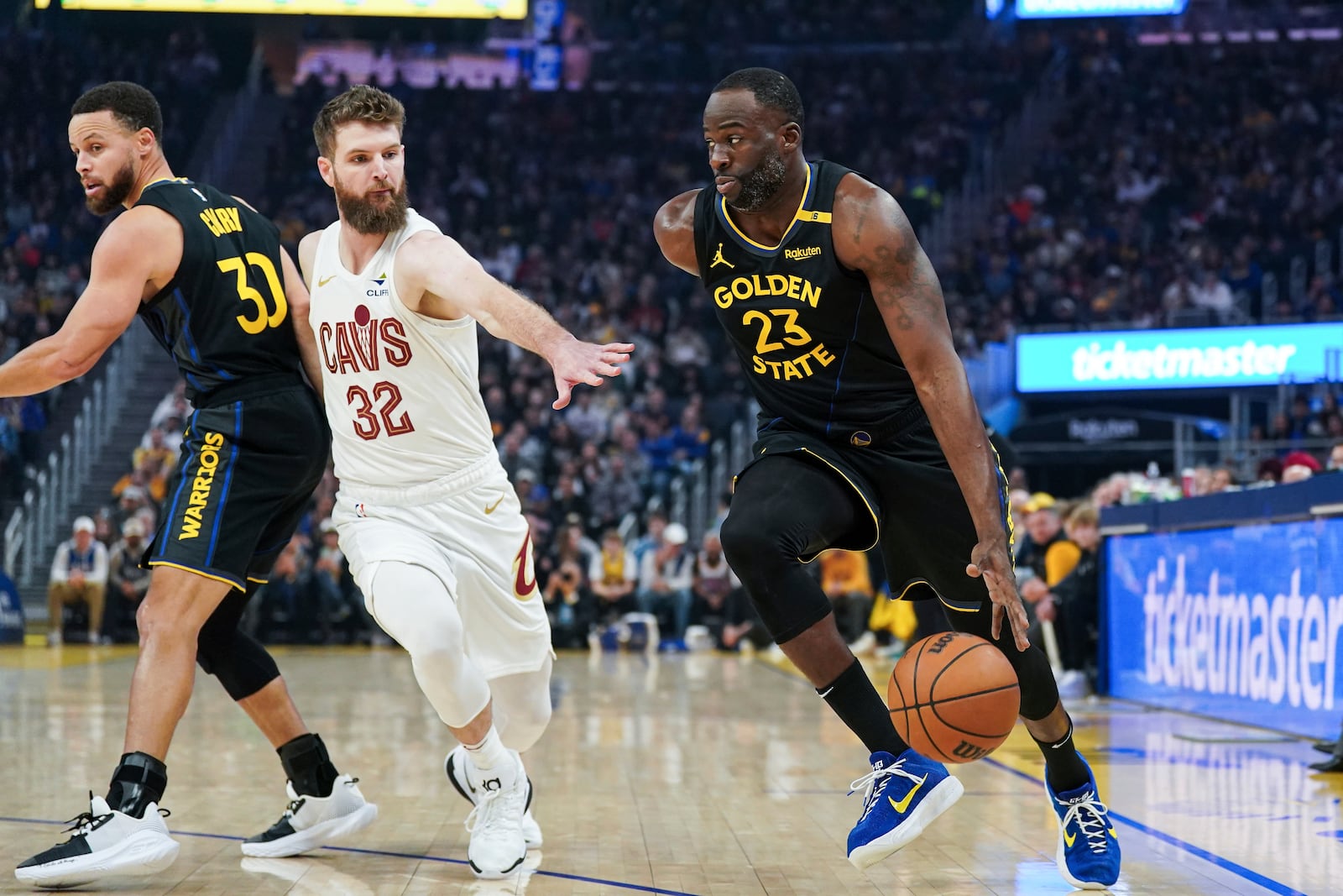 Golden State Warriors forward Draymond Green, right, moves the ball while defended by Cleveland Cavaliers guard Dean Wade (32) during the first half of an NBA basketball game Monday, Dec. 30, 2024, in San Francisco. (AP Photo/Kavin Mistry)