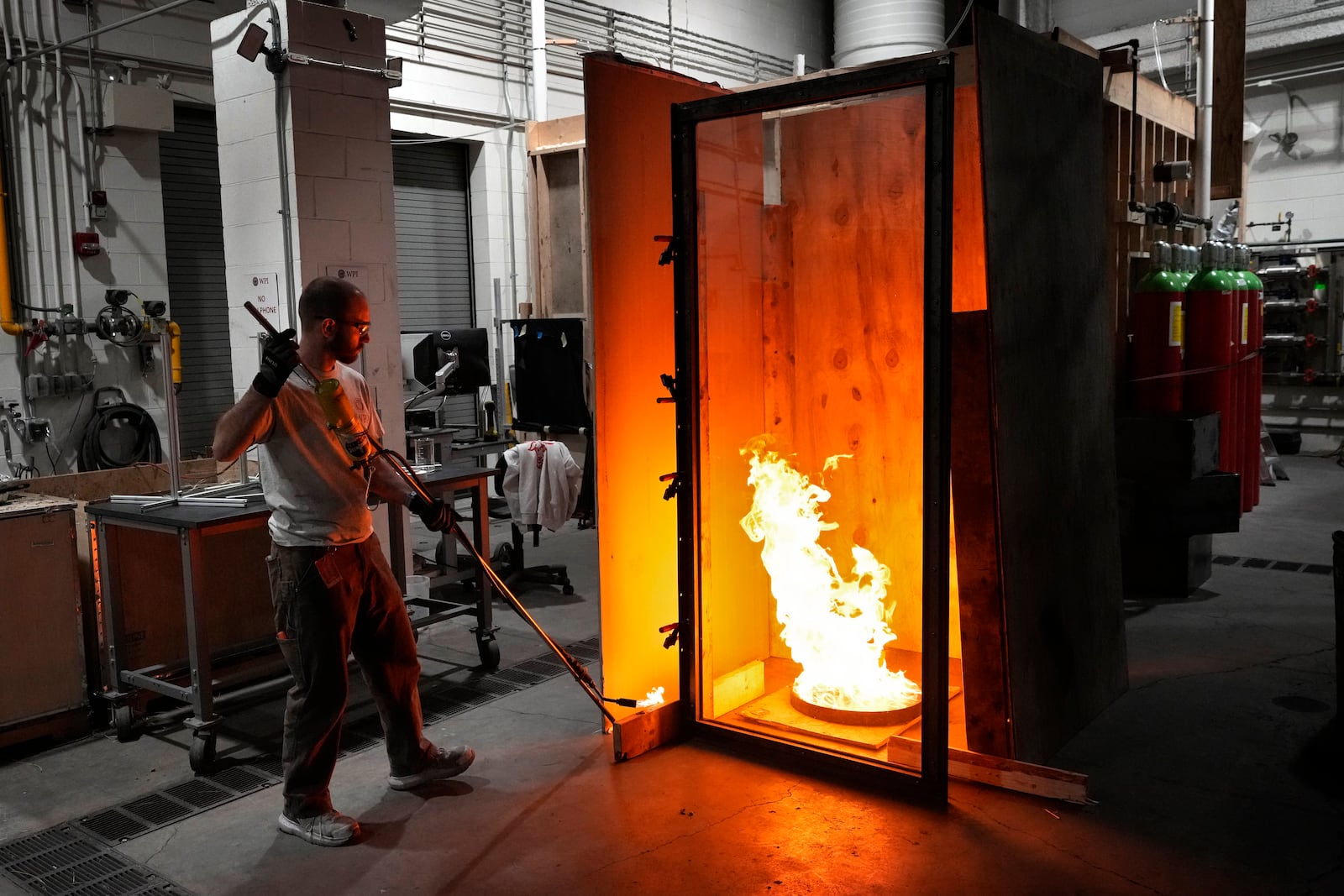 Fritz Brokaw, lab manager in the department of Fire Protection Engineering at Worcester Polytechnic Institute, ignites a test fire, Wednesday, Jan. 15, 2025, in Worcester, Mass. (AP Photo/Robert F. Bukaty)