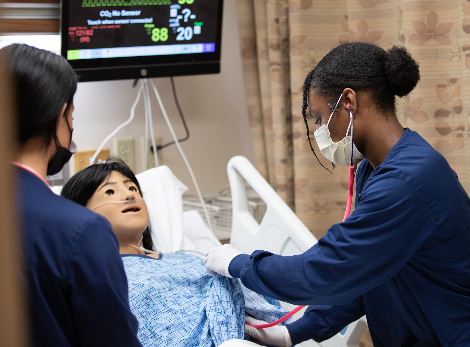 A Kettering College student practices taking vital signs on a simulation mannikin. 