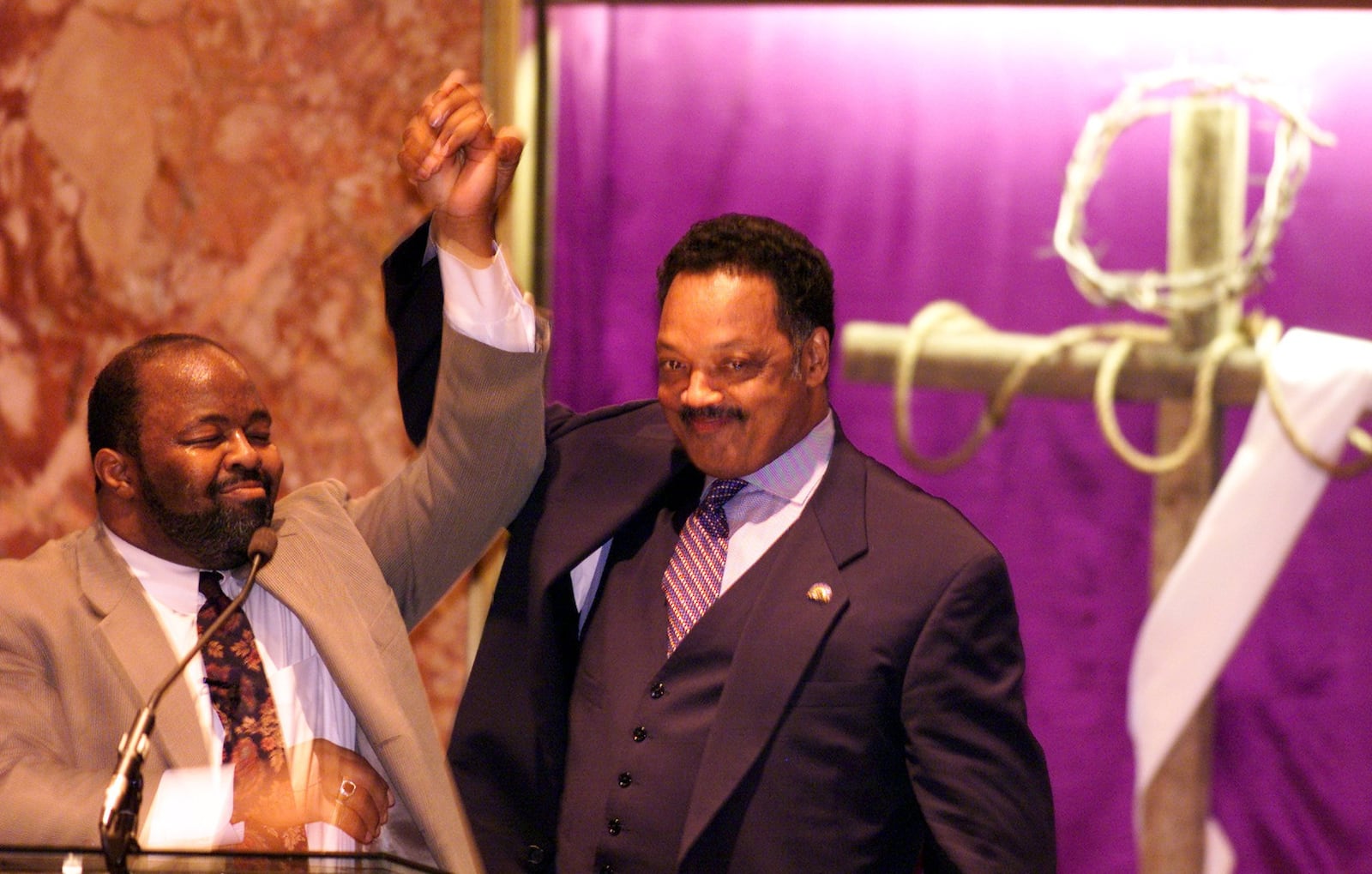 Rev. Jesse Jackson, right, raises a triumphant arm with Dr. Daryl Ward, pastor of the Omega Baptist Church, as Jackson takes the podium at the church to talk with the congregation, Sunday. Jackson, who is making his way across Ohio from Cincinnati to Youngstown encouraging people to register to vote, made several stops in the Dayton area, including Xenia.