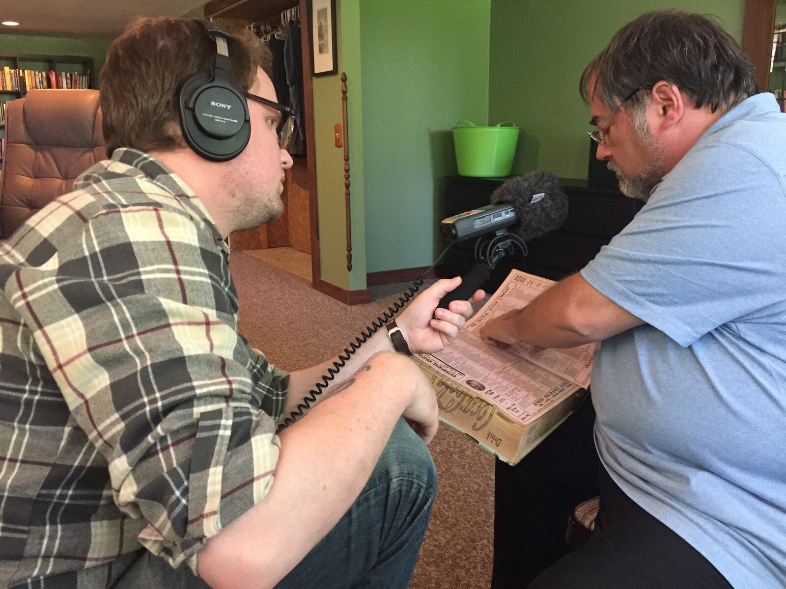 On and off over two year, George Drake  Jr. lead a team that includes his wife, Ruth Reveal, and a farmer named Jessi Sievers on a quest to piece together the real-life story behind a letter found under an Oakwood bathtub. The result if the podcast Fifth and Ludlow. Drake Jr is pictured recording Dayton Historian Curt Dalton as he looks through a city directory .