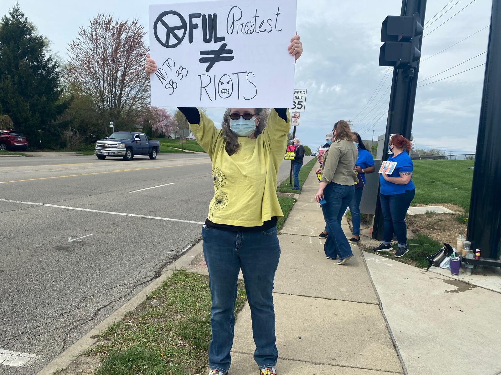 Julia Sizemore holds a sign outside of Delco Park on Far Hills Avenue on Saturday protesting proposed Ohio laws around protesting. EILEEN MCCLORY / STAFF