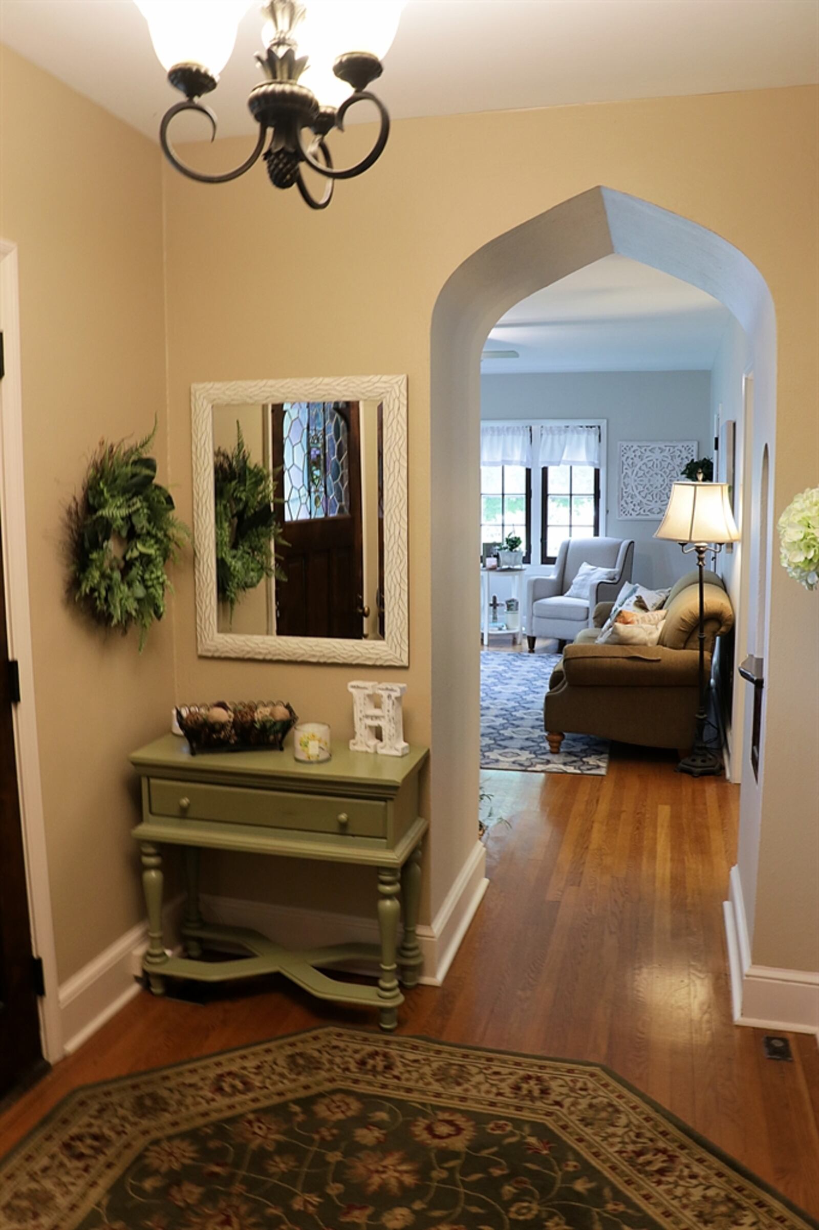 Upon entry, the foyer has a built-in telephone shelf with ornate woodwork and is currently used as an artwork nook. There is a leaded-glass door on the mail slot and arched walkways come to a pointed peak. A spindled-accented semi-open staircase leads from the foyer to the upstairs bedroom area. Kathy Tyler/CONTRIBUTED