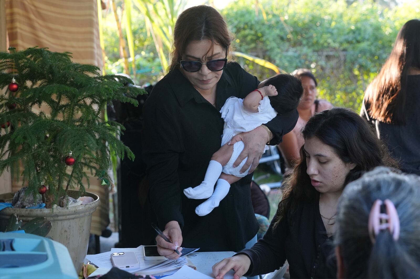 Immigration advocate Nora Sandigo signs guardianship papers for U.S.-born children whose parents are in the country illegally, Sunday, Feb. 2, 2025, in Homestead, Fla. (AP Photo/Marta Lavandier)