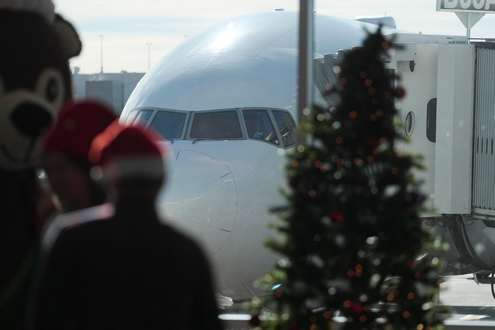 Passengers in holiday garb wait to board an airplane during the United Airlines annual "fantasy flight" to a fictional North Pole at Denver International Airport, Saturday, Dec. 14, 2024, in Denver. (AP Photo/David Zalubowski)