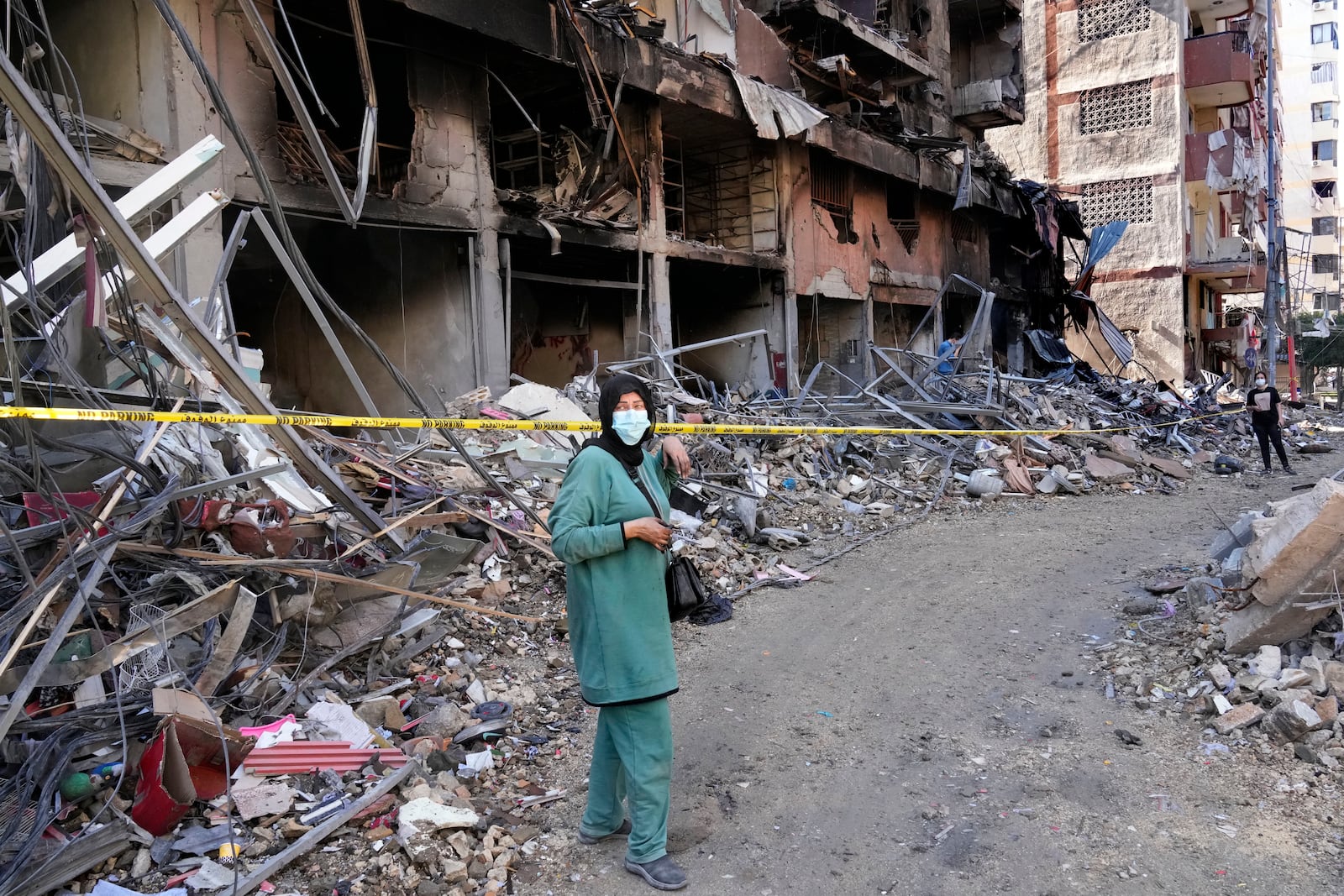 A woman stands in front of a building that was destroyed by an Israeli airstrike in Dahiyeh, in the southern suburb of Beirut, Lebanon, Monday, Nov. 11, 2024. (AP Photo/Hussein Malla)