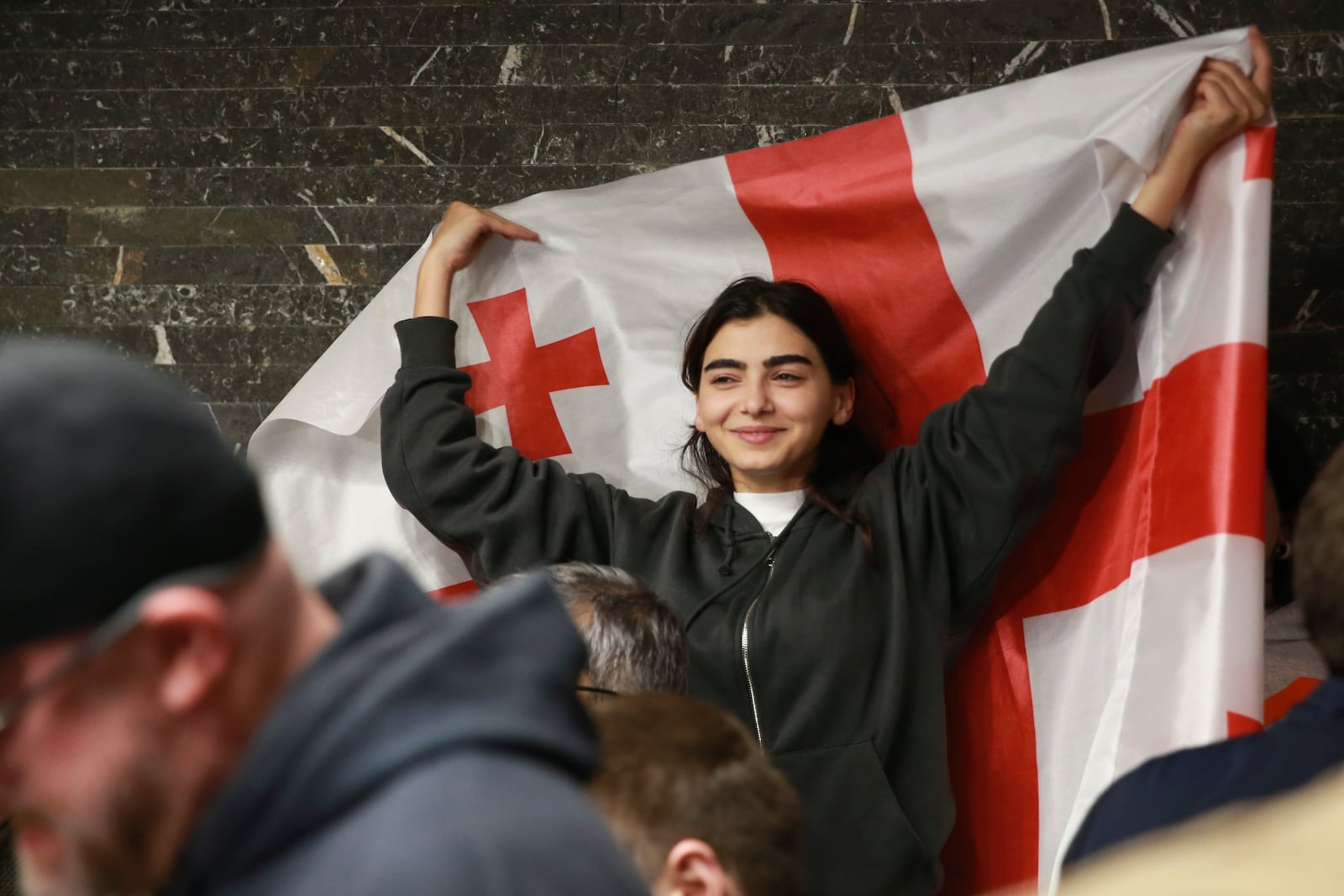 A supporter of the Coalition for Change holds a Georgian flag at coalition's headquarters after polls closing at the parliamentary election in Tbilisi, Georgia, Saturday, Oct. 26, 2024. (AP Photo/Zurab Tsertsvadze)