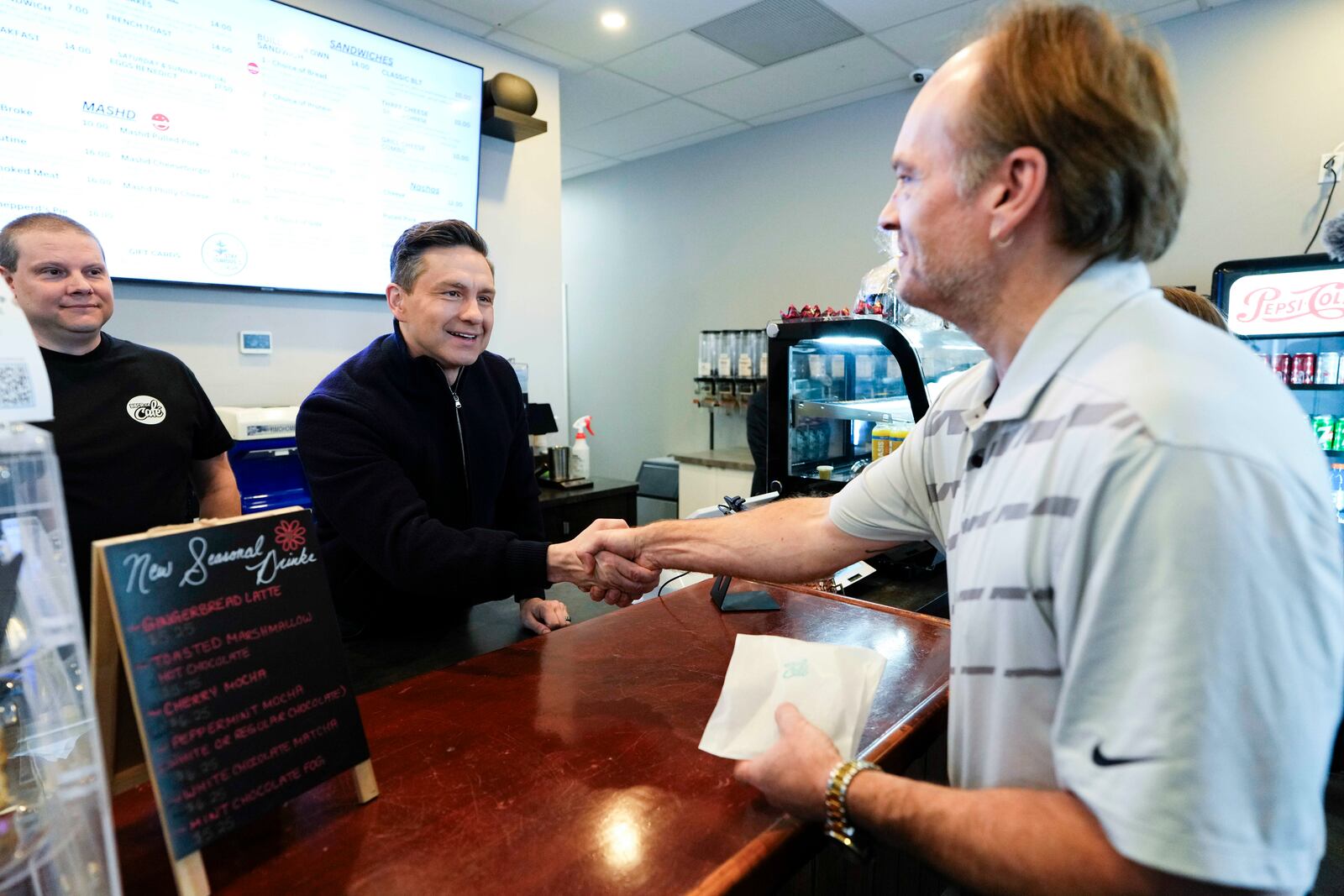 Conservative Leader Pierre Poilievre greets a supporter as he campaigns at a a cafe in the Orleans community of Ottawa, on Saturday, March 22, 2025. (Justin Tang /The Canadian Press via AP)