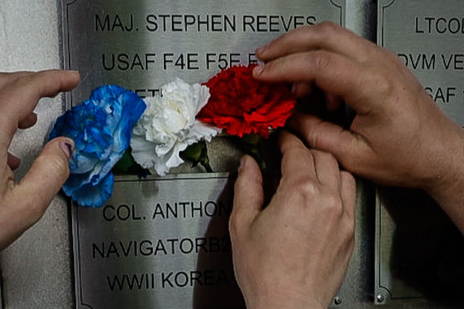 Family and friends hung flowers hear the plack of their loved ones after the Legacy Bata Plate Wall of Honor Tribute Ceremony at the Air Force Museum.  
The Air Force Museum held its first Honor Plate Ceremony since the pandemic three years ago. JIM NOELKER/STAFF