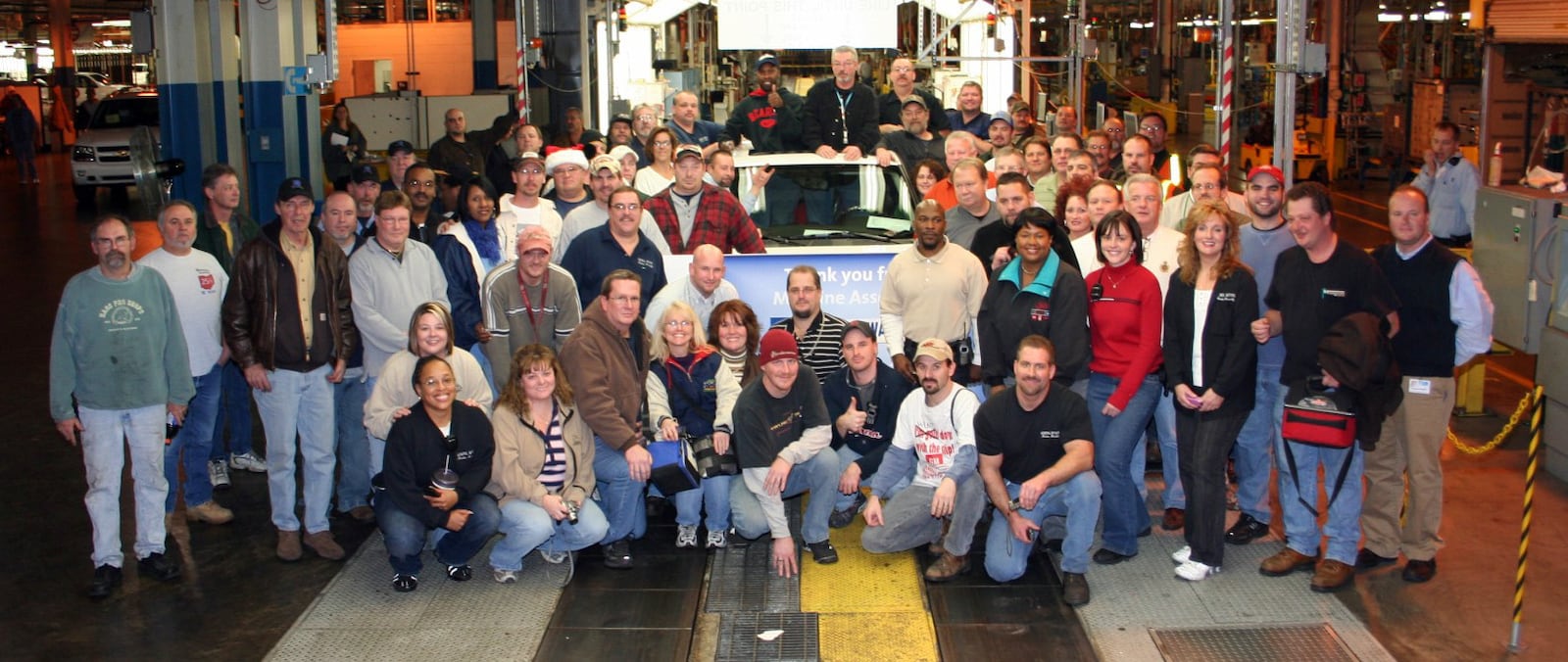 The remaining employees pose for a photo around the final GMC Envoy Denali as it comes off the line Tuesday Dec. 23 at the GM Moraine Assembly Plant.