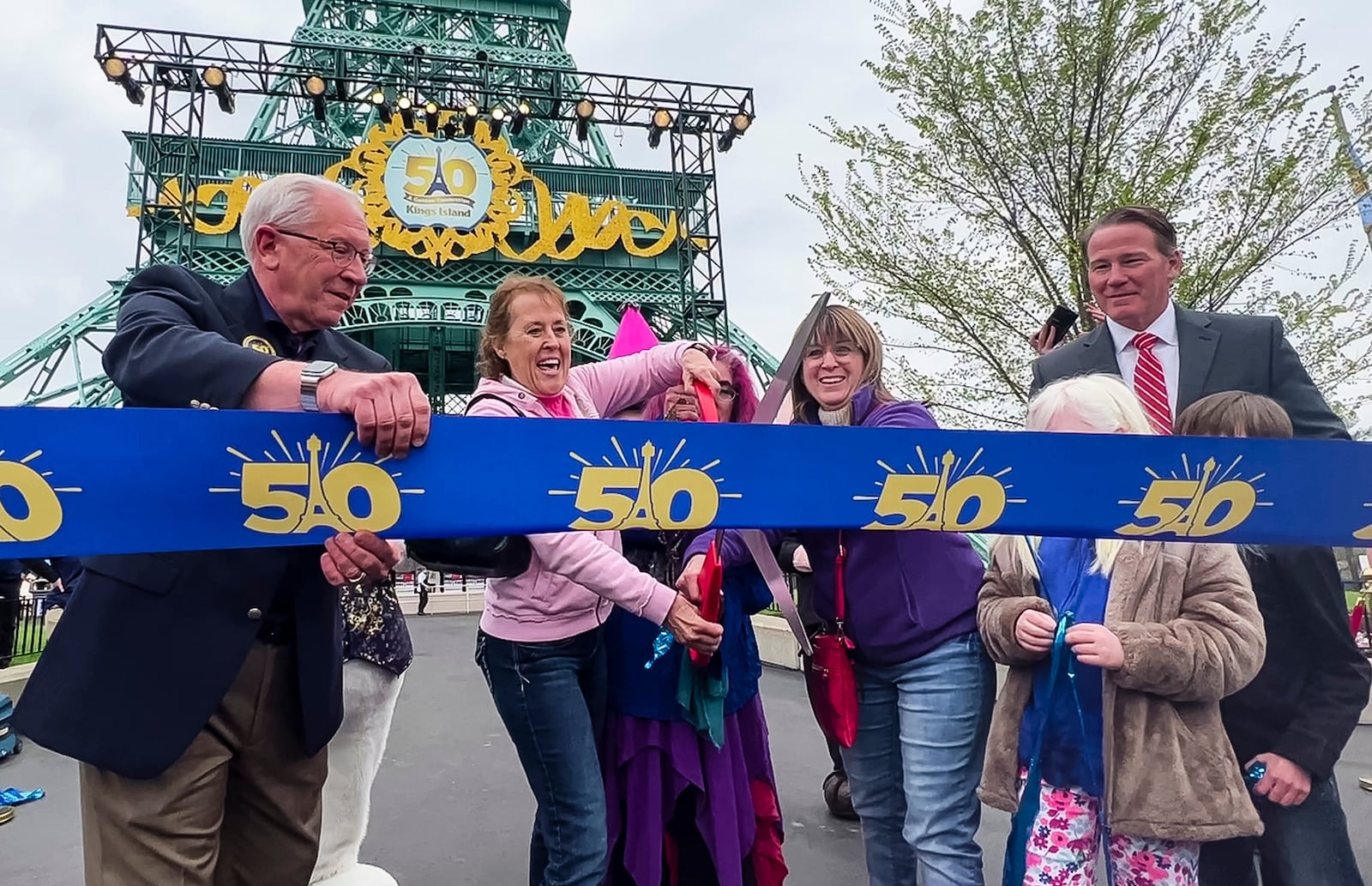 Kings Island held an opening ceremony and ribbon cutting Friday, April 29, 2022 in celebration of their 50th Anniversary. Sisters Taryn Harrison, left, Heather Lee Hitson, middle, and Tamara Hitson, cut the ribbon to kick off the 50th season. The sisters cut the ribbon 50 years ago when the park opened. Mike Koontz, Kings Island President and General Manager, left, and Ohio Lt. governor Jon Husted, right, joined them. NICK GRAHAM/STAFF