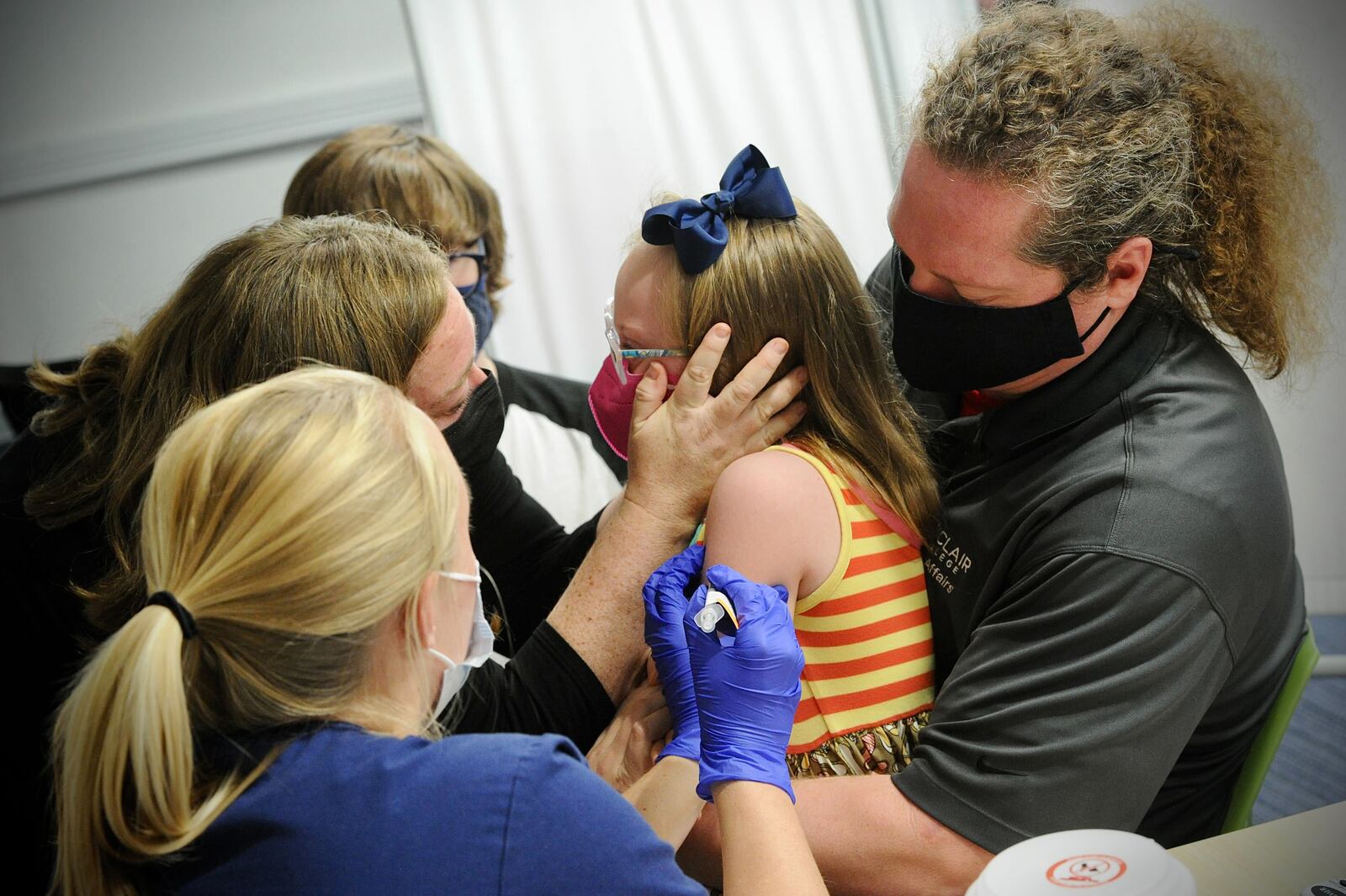 Joy Minor is held by her father Paul while talking with her mother,  Jessica as she receives her COVID-19 vaccine at Dayton Children's Monday, Nov. 8, 2021. MARSHALL GORBY\STAFF