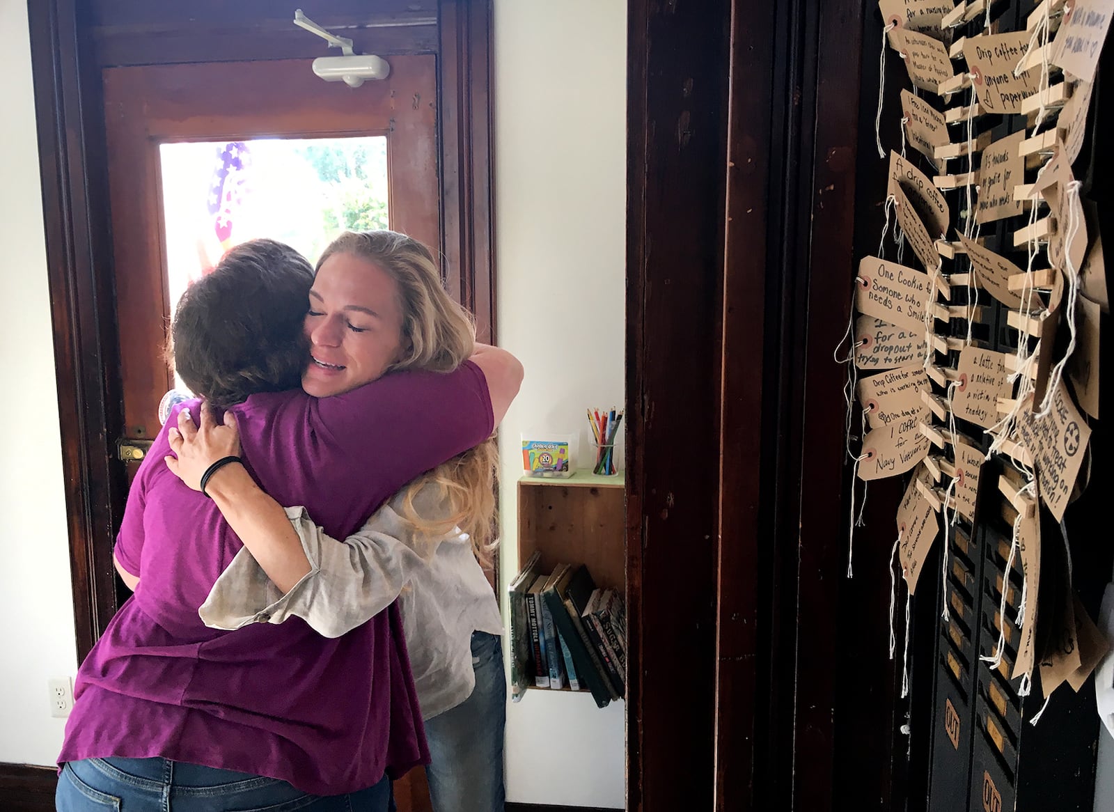 A customer embraces Megan Smith, founder of St. Anne the Tart, Friday morning at the shop located in the St. Anne's Hill neighborhood. The shop has a "Do Good" wall (right) where people can purchase something for a stranger. LISA POWELL / STAFF