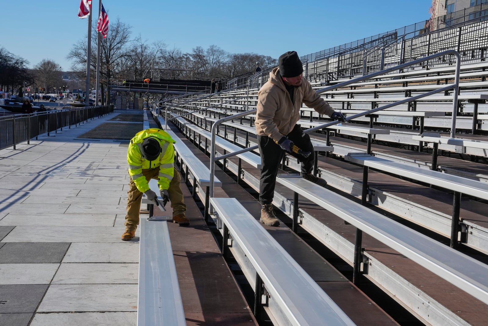 Workers continue construction on bleachers at Freedom Plaza along Pennsylvania Avenue for parade seating ahead of the upcoming inauguration of President-elect Donald Trump in Washington, Tuesday, Jan. 14, 2025. (AP Photo/Jon Elswick)