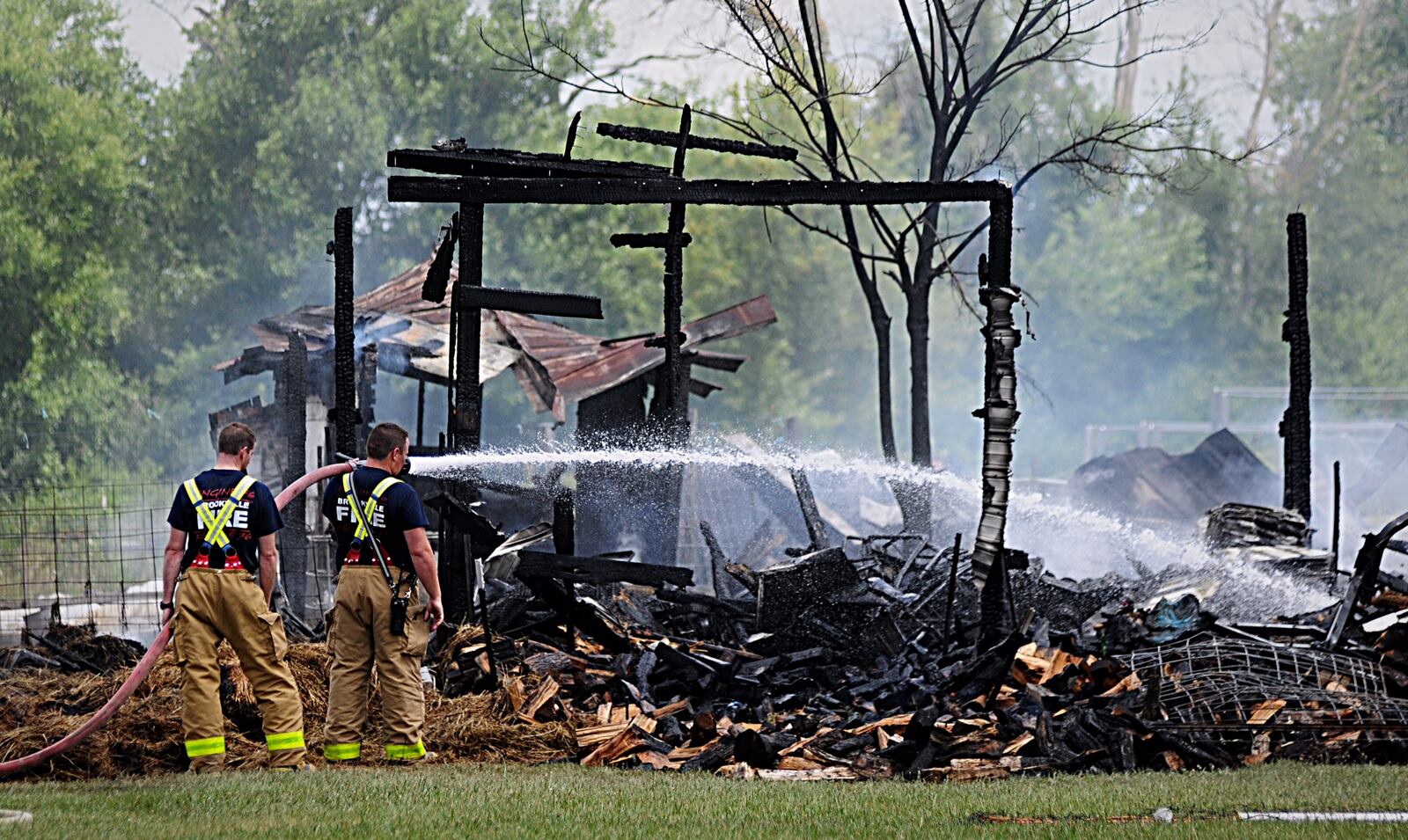 Firefighters continue to pour water onto a barn that was destroyed in a fire on Johnsville Brookville Road in Perry Twp. Thursday. (Marshall Gorby/Staff)