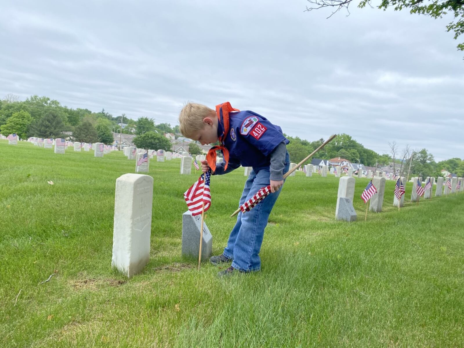 Andrew Fisher, 6, of Cub Scout Pack 402, places flags on veterans' graves at the Dayton National Cemetery on Saturday, May 29. Eileen McClory / Staff