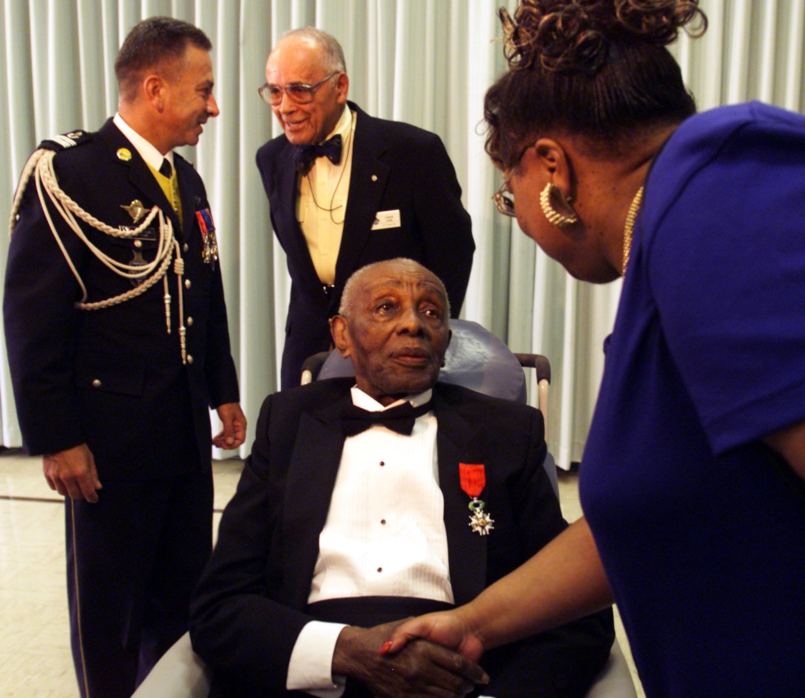 Ninety Nine year old veteran, Leonard Marbury Sr. is congratulated by Idotha Bootsie Neal, City Commissioner after receiving the French Legion of Honor award at a ceremony at the VA Medical Center today. It was presented by Colonel Marc Alain Wood, Military Attache at the French Embassy in Washington D.C. who is talking to City Commissioner, Lloyd Lewis.