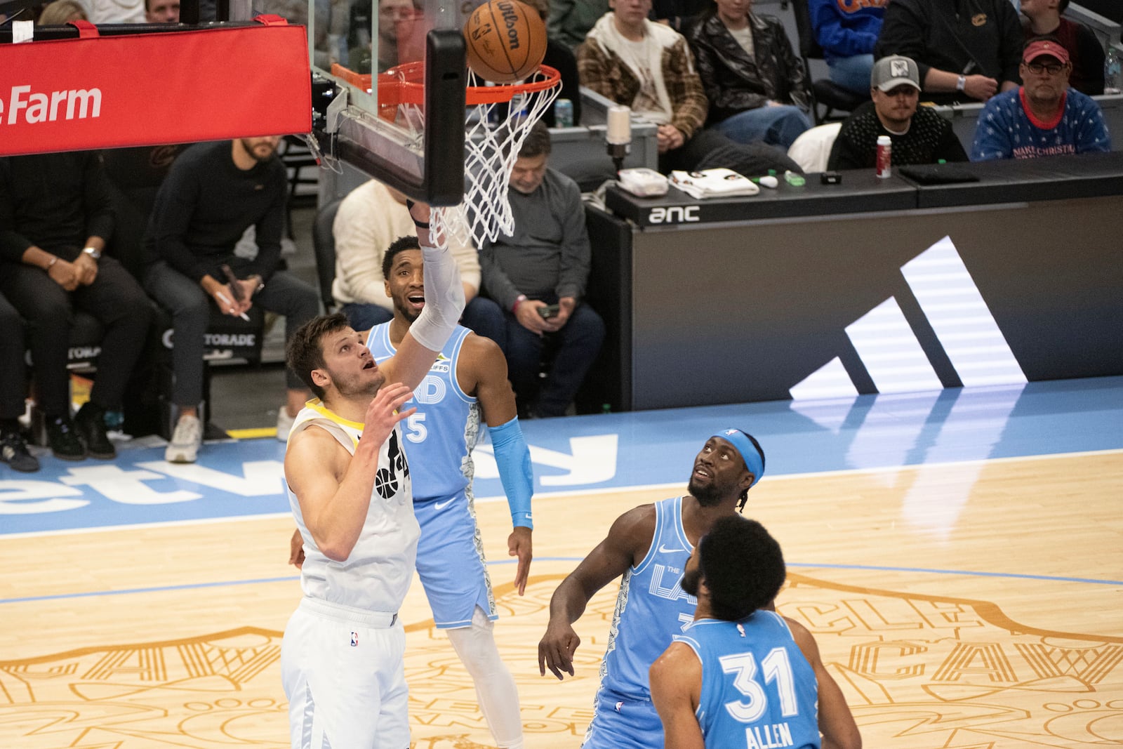 Utah Jazz Walker Kessler, left, shoots as Cleveland Cavaliers' Donovan Mitchell, rear, Caris LeVert, right center, and Jarrett Allen (31) stand by during the first half of an NBA basketball game in Cleveland, Monday Dec. 23, 2024. (AP Photo/Phil Long)