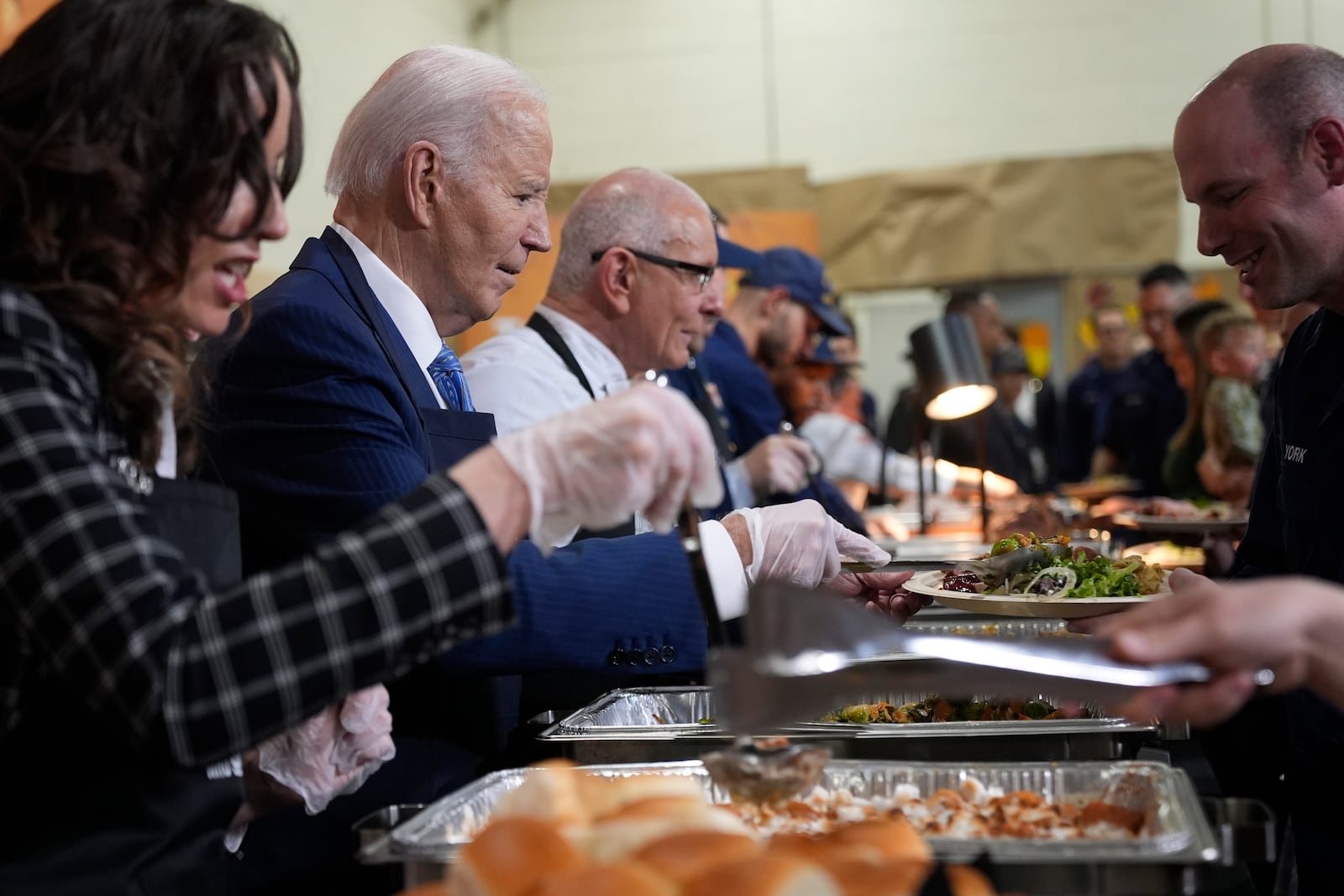 President Joe Biden, from second left, and chef Robert Irvine serve food at a Friendsgiving event with service members and their families in the Staten Island borough of New York, Monday, Nov. 25 2024. (AP Photo/Manuel Balce Ceneta)