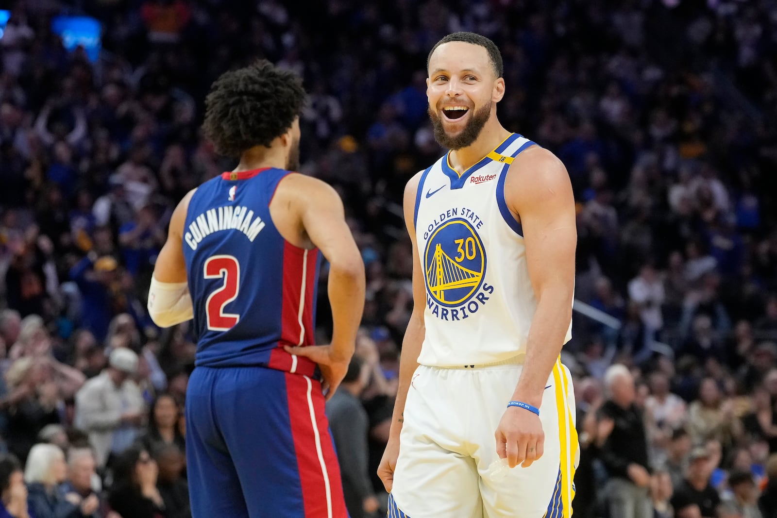 Golden State Warriors guard Stephen Curry (30) walks past Detroit Pistons guard Cade Cunningham (2) and smiles toward the Pistons' bench during the second half of an NBA basketball game in San Francisco, Saturday, March 8, 2025. (AP Photo/Jeff Chiu)