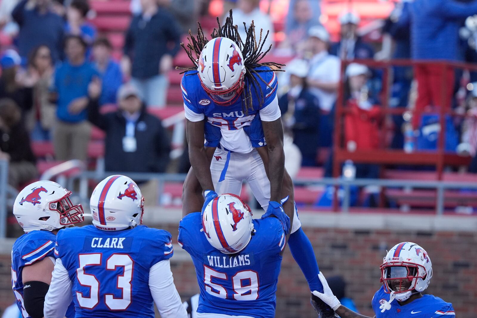 SMU wide receiver Derrick McFall (20) is lifted by teammate defensive end Isaiah Smith (58) after McFall scored a touchdown during the first half of an NCAA college football game against California, Saturday, Nov. 30, 2024, in Dallas. (AP Photo/LM Otero)