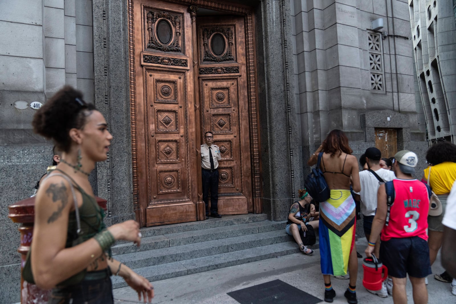 A private security guard watches as people gather in Buenos Aires, Argentina, Saturday, Feb. 1, 2025, for a protest against President Javier Milei’s speech at the World Economic Forum in Davos, during which he criticized “sick wokeism,” social welfare, feminism, identity politics and the fight against climate change. (AP Photo/Rodrigo Abd)