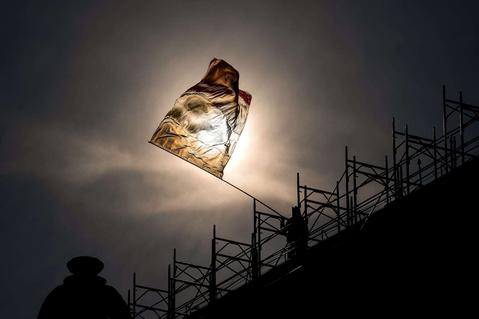 A man perched on the roof of a building waves the Romanian flag during a rally organized by the right wing Alliance for the Unity of Romanians (AUR), calling for free elections after Romania' s Constitutional Court annulled the first round of presidential elections last December, in Bucharest, Romania, Sunday, Jan. 12, 2025. (AP Photo/Vadim Ghirda)