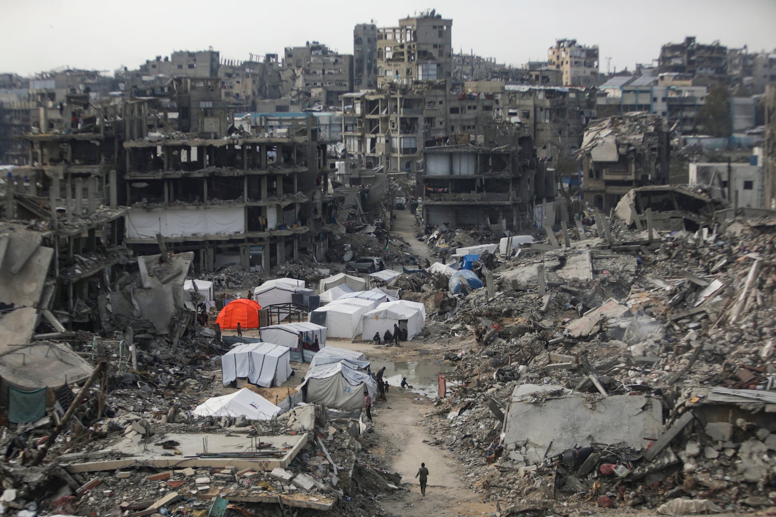 People walk amid the destruction caused by the Israeli air and ground offensive in Jabaliya, Gaza Strip, on Tuesday, Feb. 18, 2025. (AP Photo/Jehad Alshrafi)