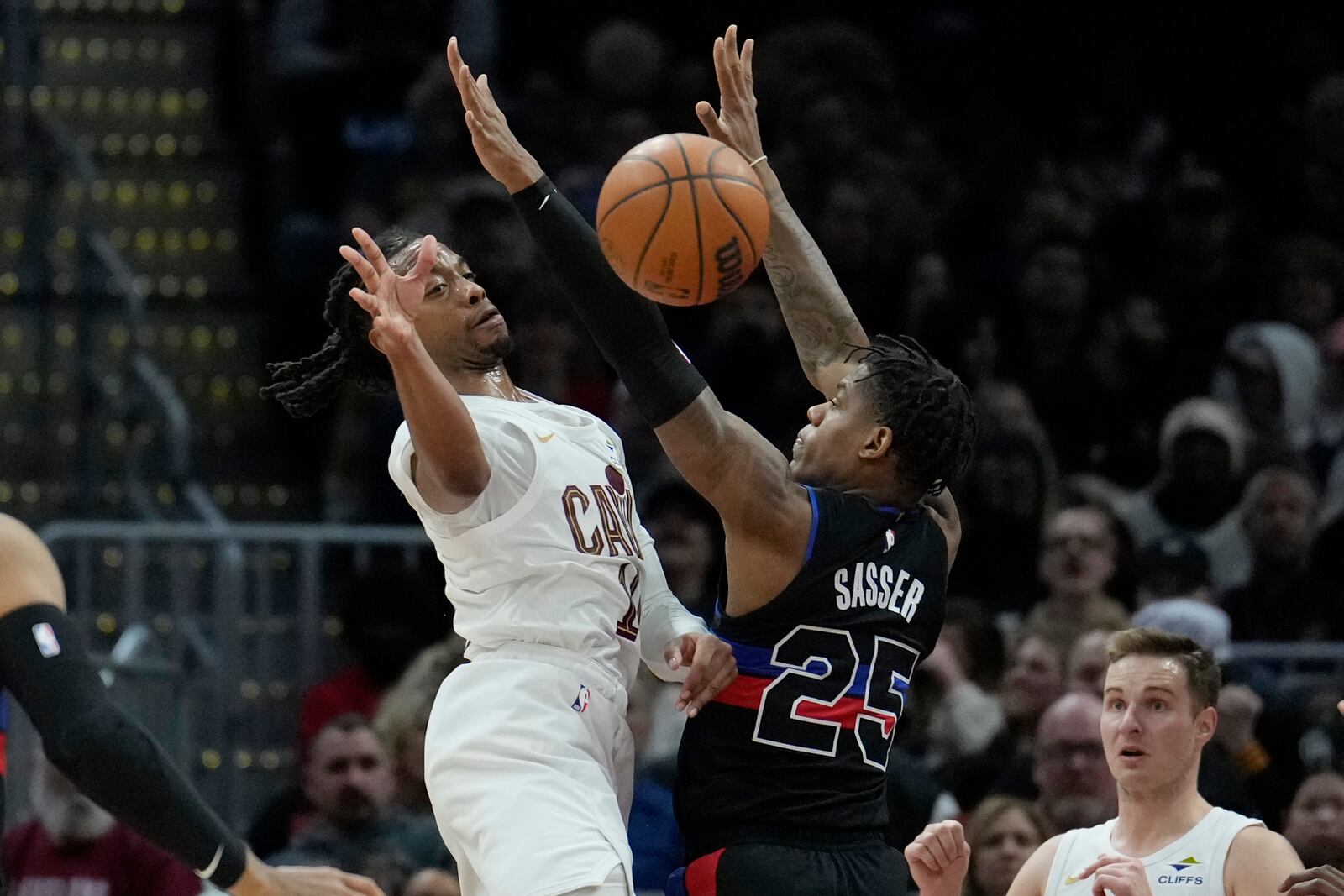 Cleveland Cavaliers guard Darius Garland, left, passes around Detroit Pistons guard Marcus Sasser (25) in the second half of an NBA basketball game, Monday, Jan. 27, 2025, in Cleveland. (AP Photo/Sue Ogrocki)