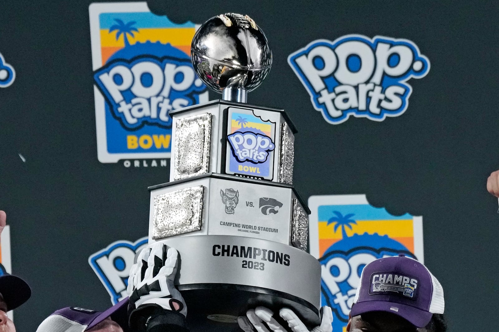 FILE - Kansas State players hold up the championship trophy after winning the Pop-Tarts Bowl NCAA college football game against North Carolina State, Thursday, Dec. 28, 2023, in Orlando, Fla. (AP Photo/John Raoux, File)