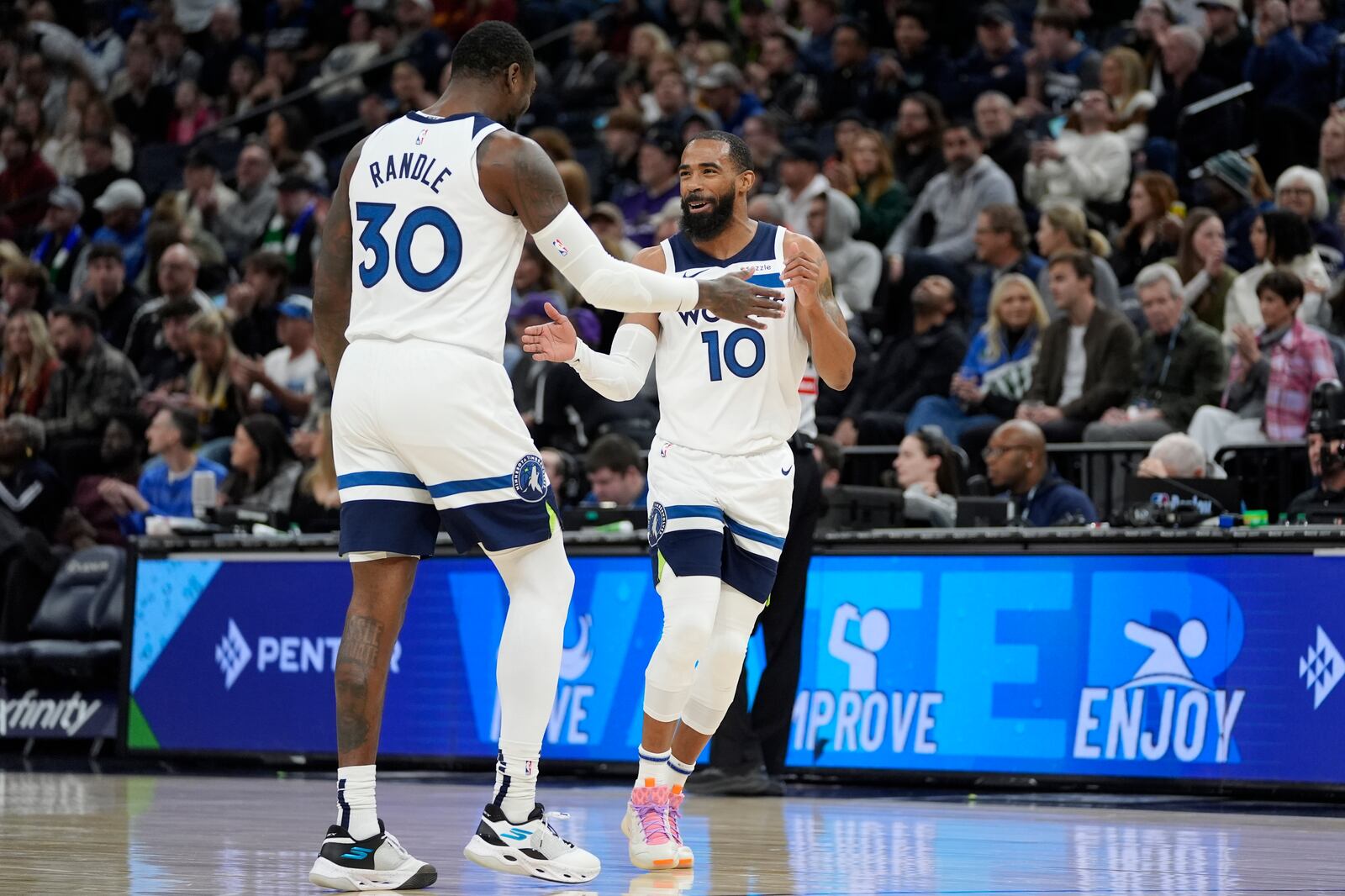 Minnesota Timberwolves guard Mike Conley (10) celebrates toward forward Julius Randle (30) after making a 3-point shot during the first half of an NBA basketball game against the Cleveland Cavaliers, Saturday, Jan. 18, 2025, in Minneapolis. (AP Photo/Abbie Parr)