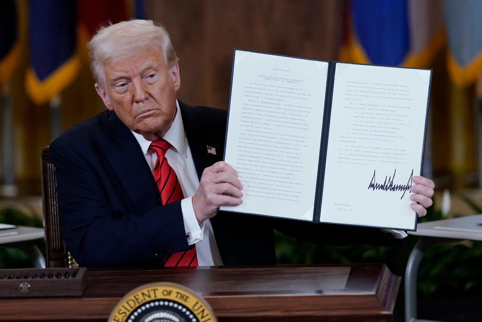 President Donald Trump holds up a signed executive order in the East Room of the White House in Washington, Thursday, March 20, 2025. (AP Photo/Jose Luis Magana)