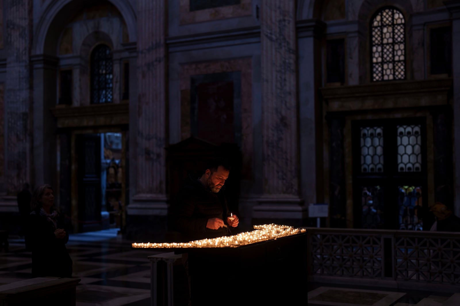 A man lights a candle inside the St. Paul's Outside The Walls Basilica in Rome, Wednesday, Feb. 26, 2025. (AP Photo/Bernat Armangue)