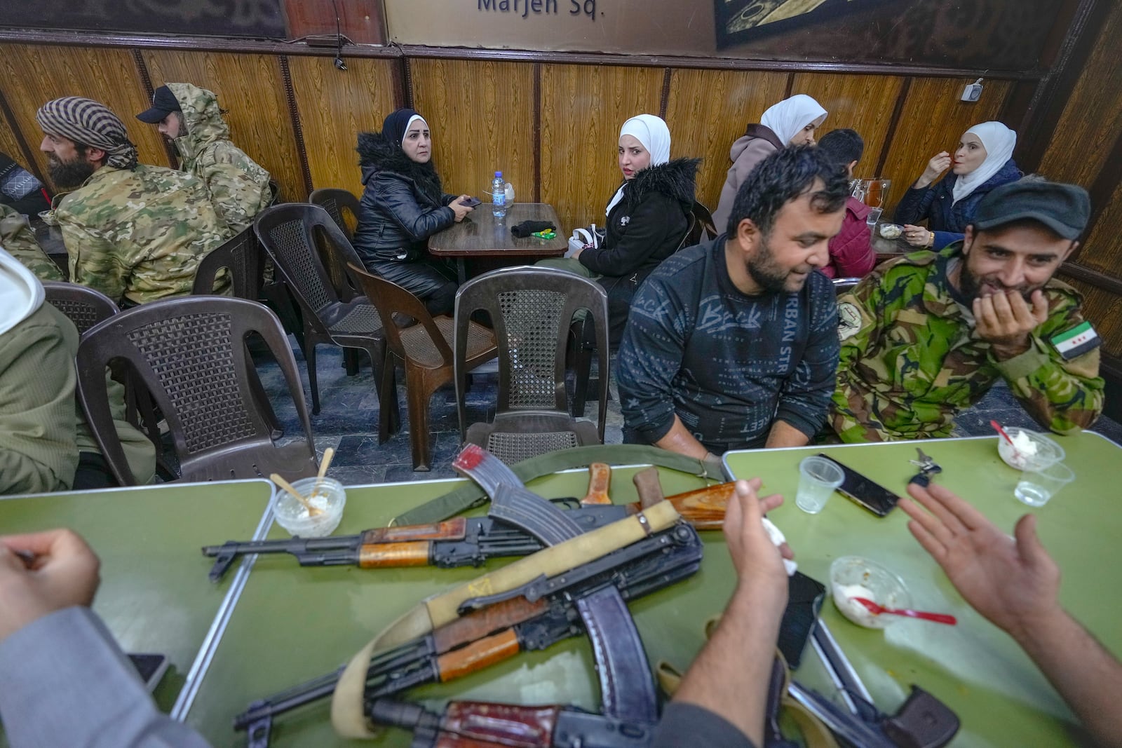 Opposition fighters sit at a restaurant at the Al-Hamidiyeh market inside the old walled city of Damascus, Syria, Tuesday, Dec. 10, 2024. (AP Photo/Hussein Malla)