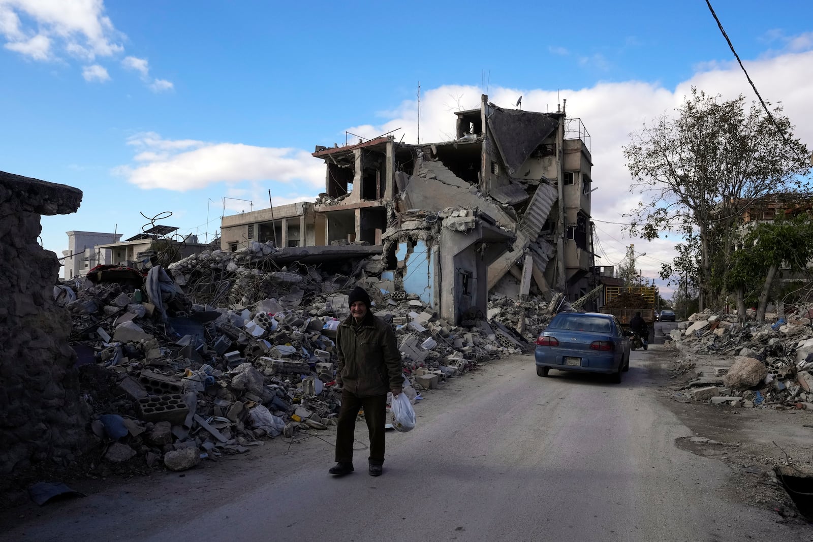 An elderly man walks near damaged buildings in Baalbek, eastern Lebanon, Thursday, Nov. 28, 2024. (AP Photo/Hassan Ammar)