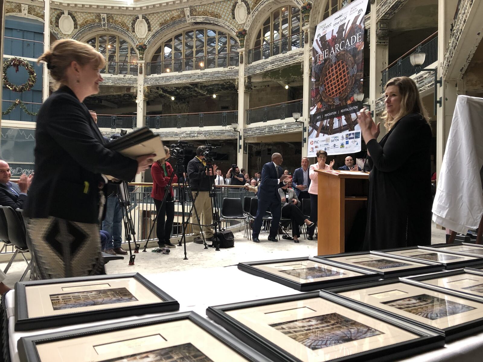 Dayton City Manager Shelley Dickstein and Mayor Nan Whaley hand out framed photos honoring city staff and community members who helped keep the vision for the Dayton Arcade alive. The arcade developers have closed on $90 million in financing for the project. CORNELIUS FROLIK / STAFF