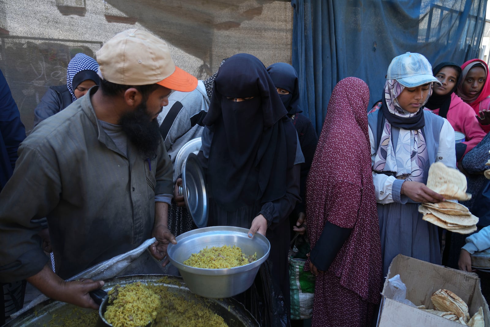 Palestinians queue for food distribution in Deir al-Balah, Gaza Strip, Friday, Feb. 14, 2025. (AP Photo/Abdel Kareem Hana)