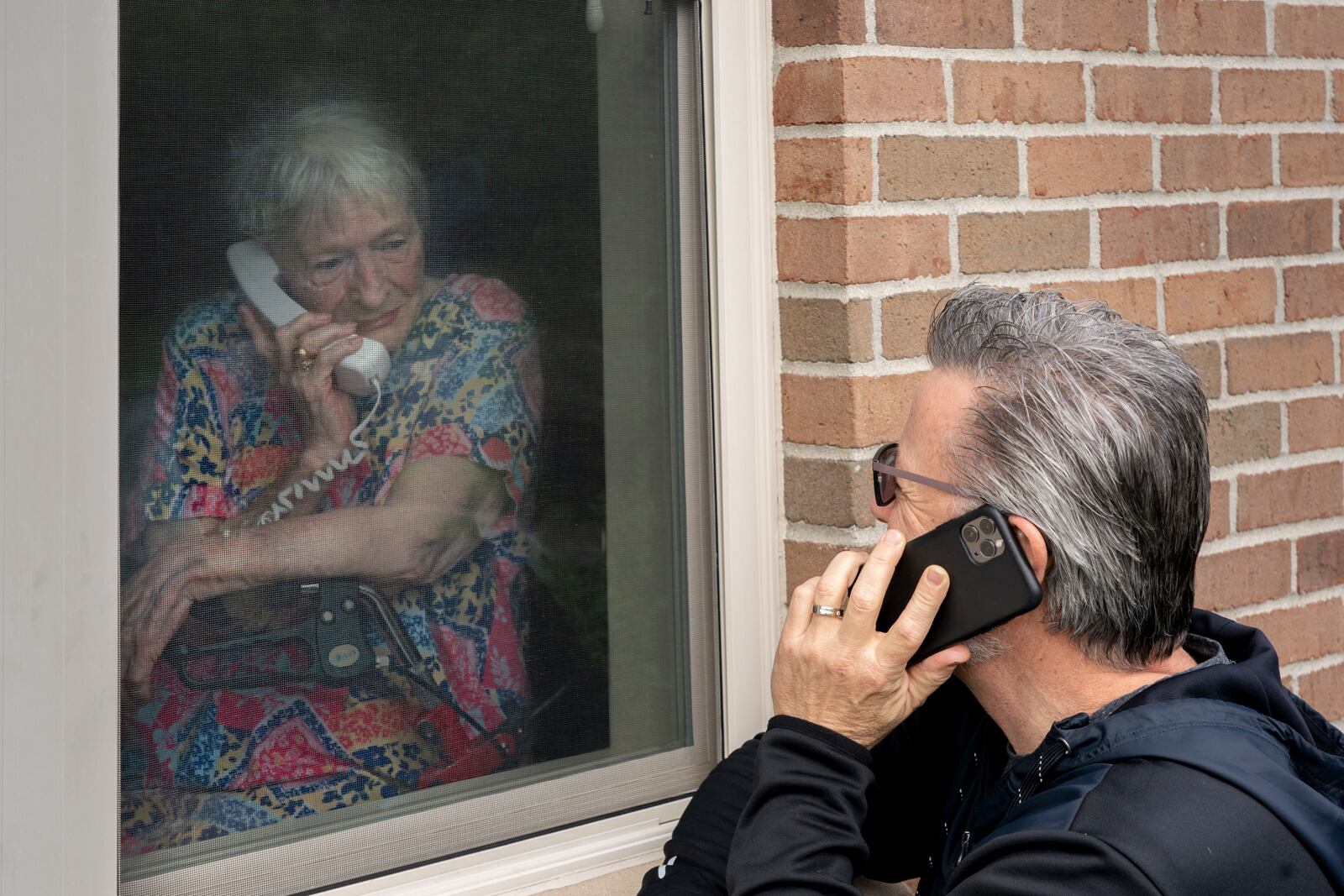 Paul Bruce: "Together, Apart," one of the selected images highlighted in The Contemporary and Dayton Daily News collaboration "In the Balance: Reflections of Our Community During COVID." "I have been fascinated by the way family and community have figured out ways to communicate in these trying times. Chris could visit his mom and talk through the screen. Then a nursing home assistant came by to say the window could not be open. Now what? 'I’ll call you mom!' So Chris and his mother, June, were able to communicate and still stay safe. These times are bizarre and can be scary. But we adapt, to keep things in the balance."