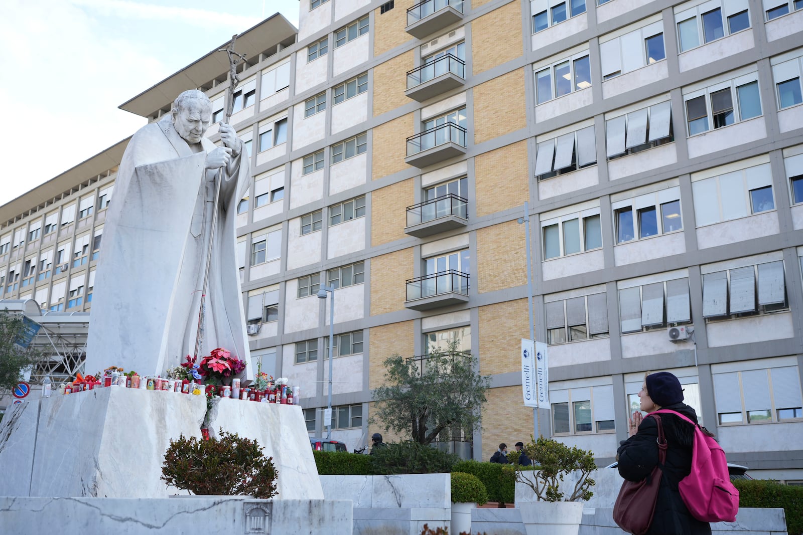 A woman prays in front of a statue of Pope John Paul II in front of the Agostino Gemelli Polyclinic, in Rome, Thursday, Feb. 20, 2025, where the Pontiff is hospitalized since Friday, Feb. 14.(AP Photo/Alessandra Tarantino)