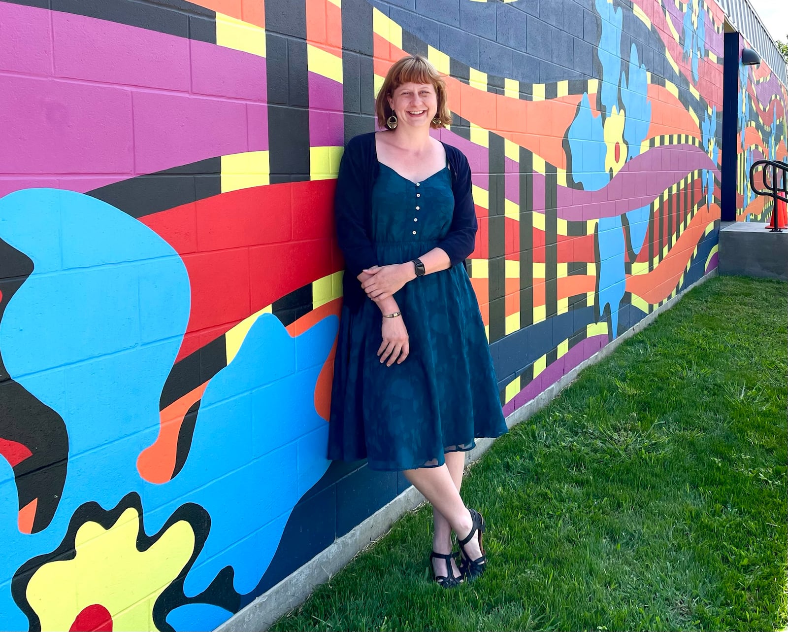 Shayna McConville at Rosewood Arts Center in front of a mural by Atalie Gagnet.