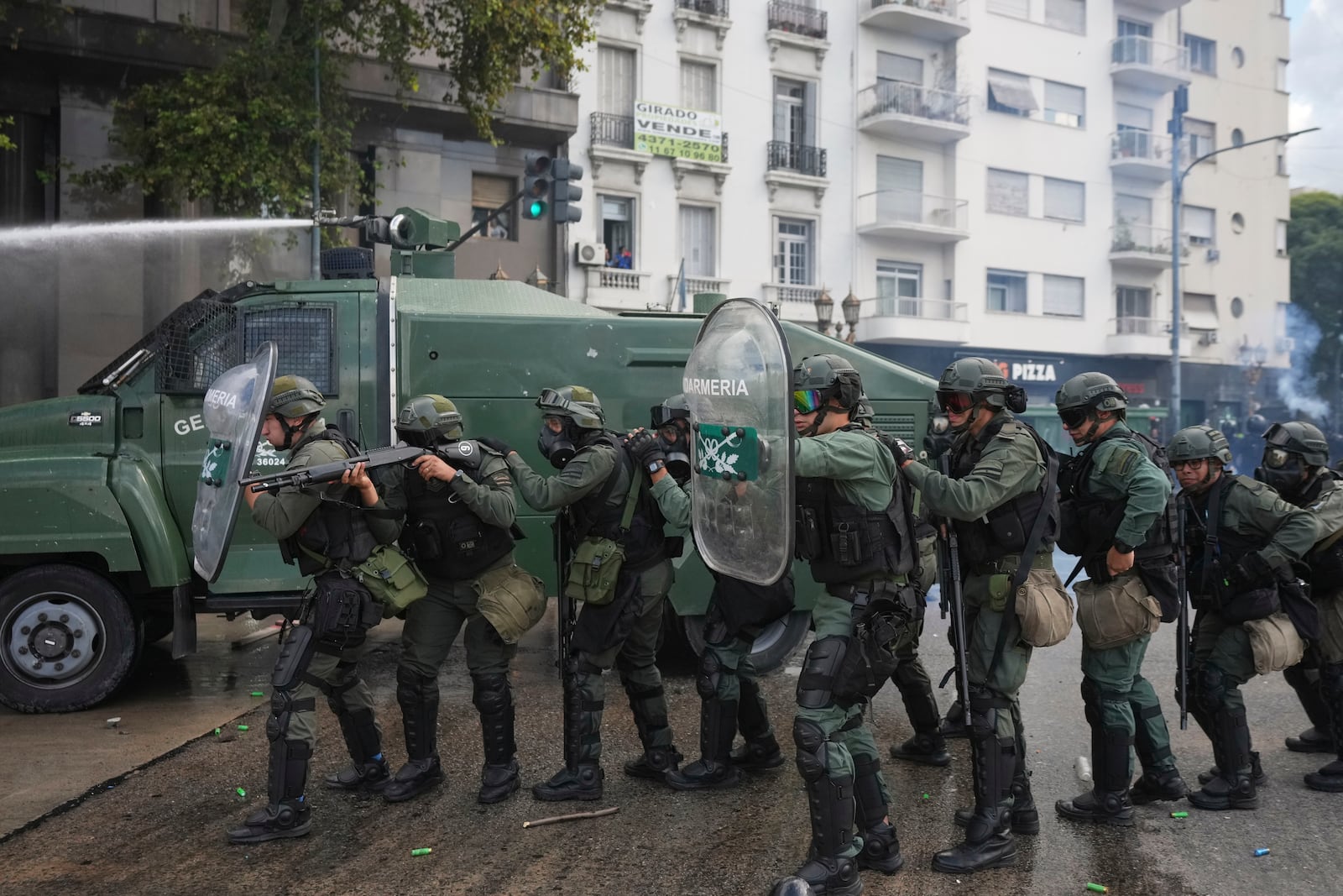 Police hold up shields during clashes against soccer fans who joined retirees protesting for higher pensions and against austerity measures implemented by Javier Milei's government in Buenos Aires, Argentina, Wednesday, March 12, 2025. (AP Photo/Rodrigo Abd)