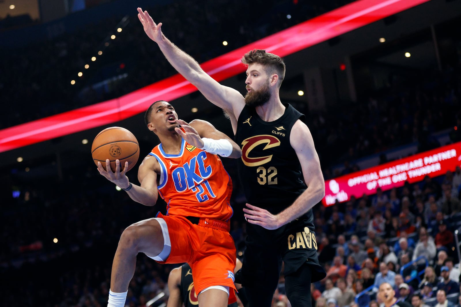 Oklahoma City Thunder guard Aaron Wiggins (21) goes to the basket against Cleveland Cavaliers forward Dean Wade (32) during the first half of an NBA basketball game Thursday, Jan. 16, 2025, in Oklahoma City. (AP Photo/Nate Billings)