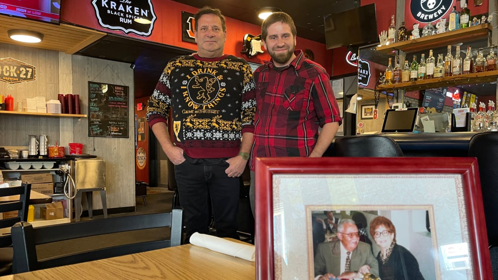 Hank's Local, located at 2529 Patterson Road in Dayton, is celebrating its 45th anniversary. Pictured (left to right) is owner Christopher Shay and his son, Chadd, standing behind a picture of Hank Duff and her husband, the original owners of the bar. NATALIE JONES/STAFF