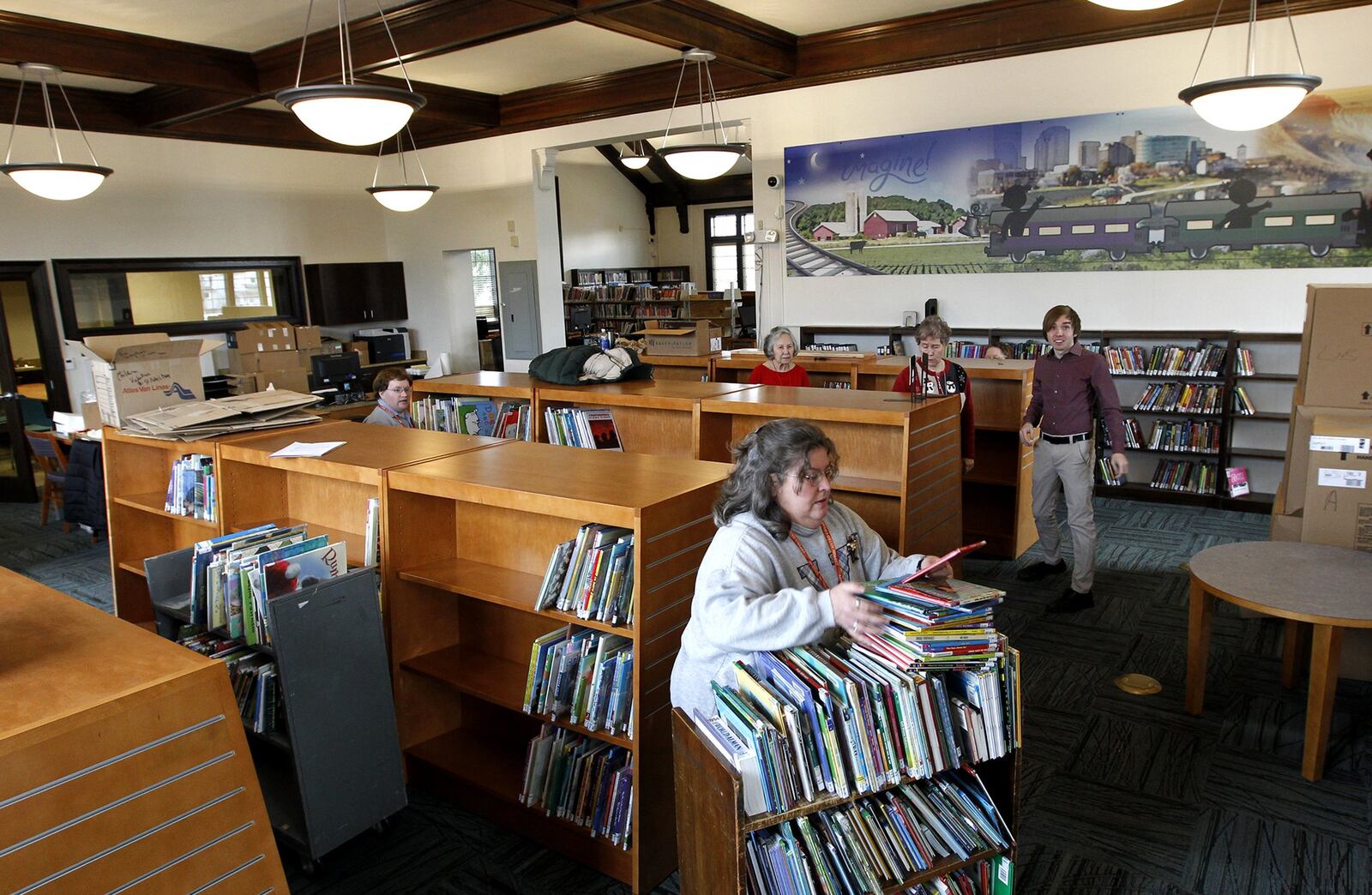 Library employees, including Jeanette Dohner, a library technical assistant, (foreground) stack books on shelves at the renovated Electra C. Doren Branch Library. The branch is the first completed project in the $187 million “Libraries for a Smarter Future” plan. An open house for the library branch will be held Saturday. LISA POWELL / STAFF PHOTO