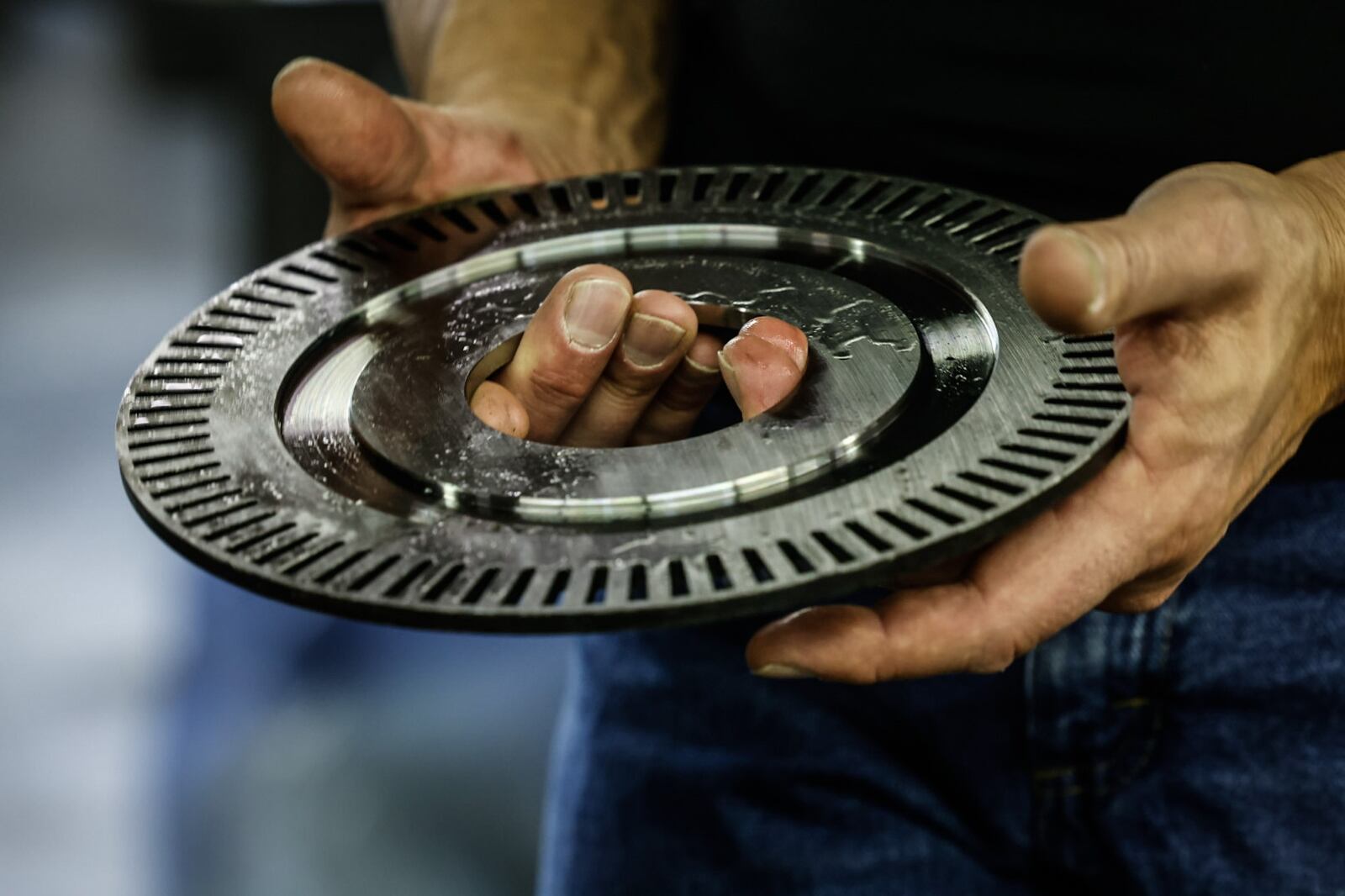 Tom Johnson holds a machined component in his West Carrollton shop that is celebrating 20 years in business. JIM NOELKER/STAFF