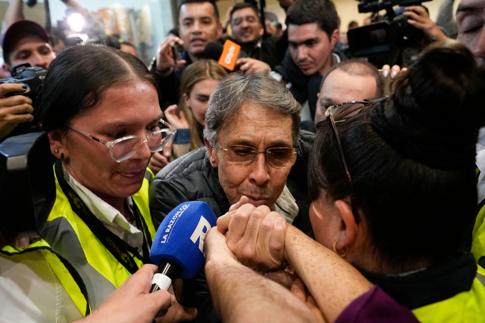 Fabio Ochoa, center, a former member of Cartel of Medellin, kisses a relative's hand upon his arrival at El Dorado airport, after being deported from the United States, in Bogota, Colombia, Monday, Dec. 23, 2024. (AP Photo/Fernando Vergara)