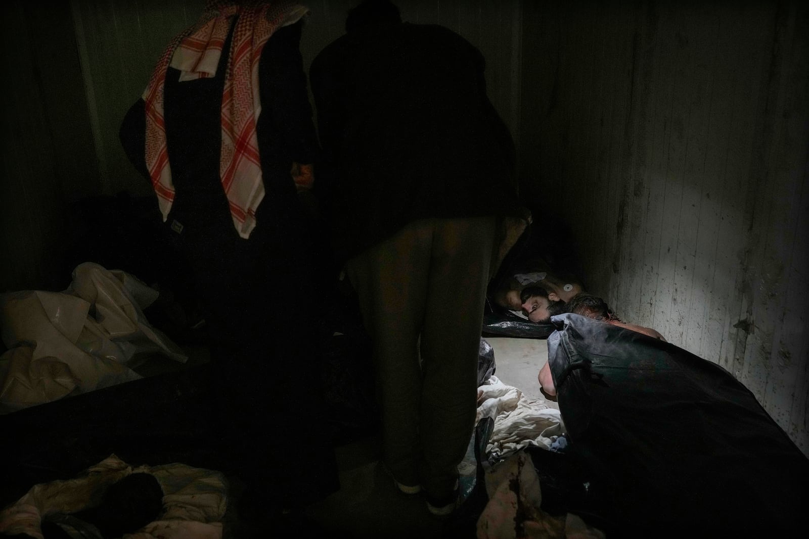 Men examine bodies as they search for missing people at the morgue of Al-Mojtahed Hospital in Damascus, Syria, on Wednesday, Dec. 11, 2024. Many are flocking to morgues, hoping to identify loved ones who were either killed or imprisoned under President Bashar Assad's government, which collapsed over the weekend. (AP Photo/Hussein Malla)